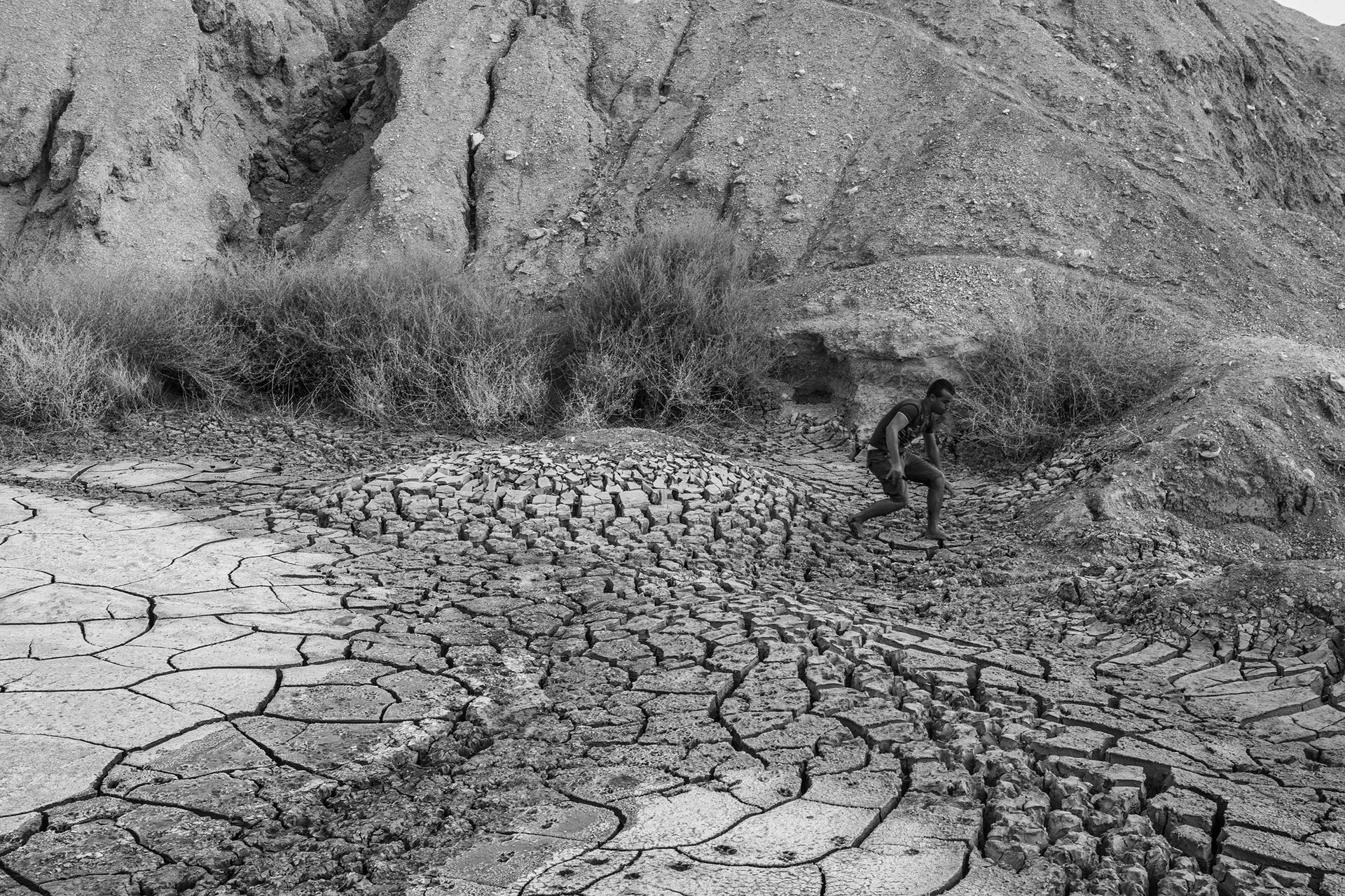 A man crosses an outflow of dried, muddy chemical waste in Al-Mitlawi, Gafsa, Tunisia. Phosphate, Tunisia&rsquo;s main export commodity, comes from mines in the Gafsa region and is one of the main sources of state income. Many waterways are contaminated by waste products created during the production of phosphoric acid.