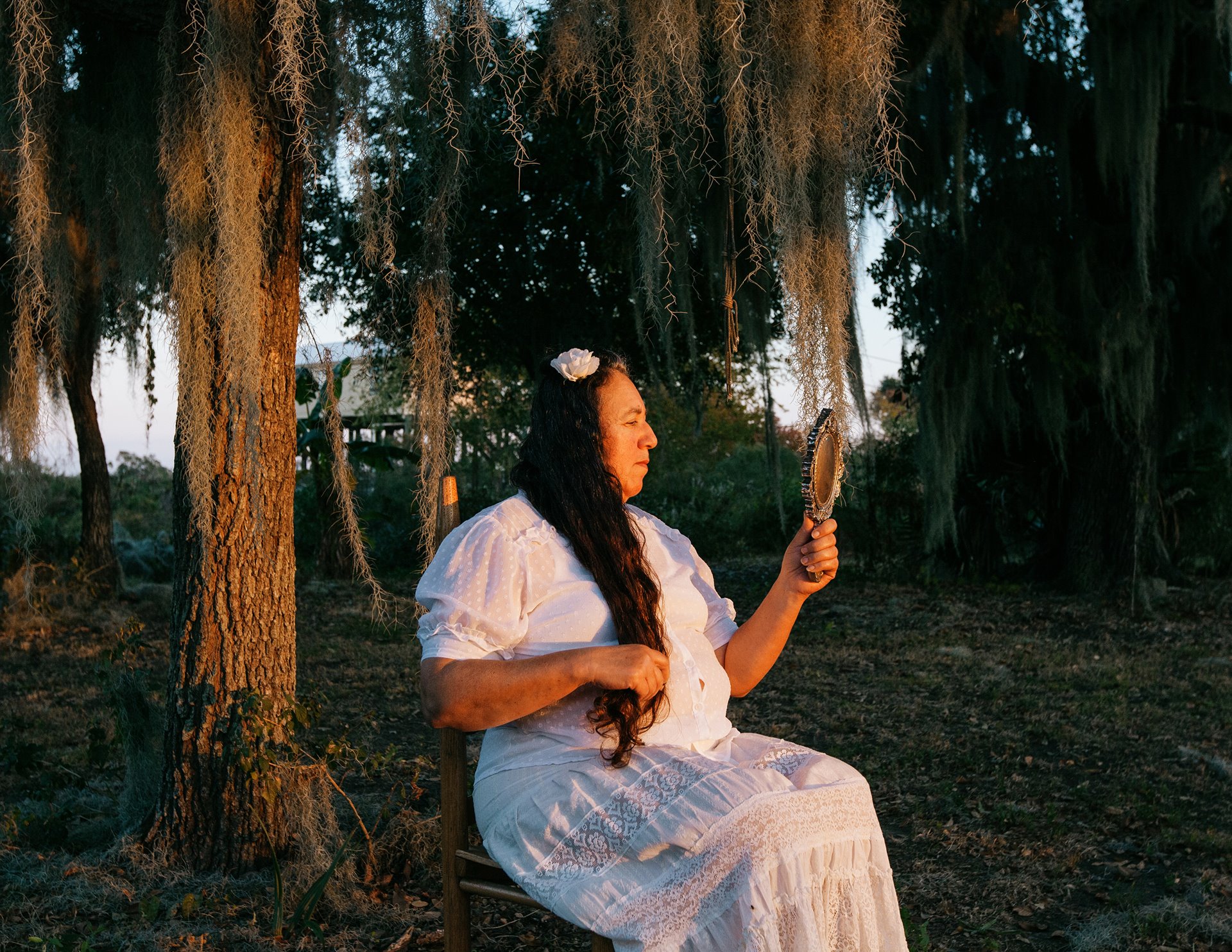 Theresa Billiot sits in her family garden in front of some of the last remaining oak trees left on Isle de Jean-Charles, in southeastern Louisiana, United States. After the death of her parents, Denecia and Wenceslaus, Theresa was the only member of her family to be resettled in Gray, Louisiana.&nbsp;