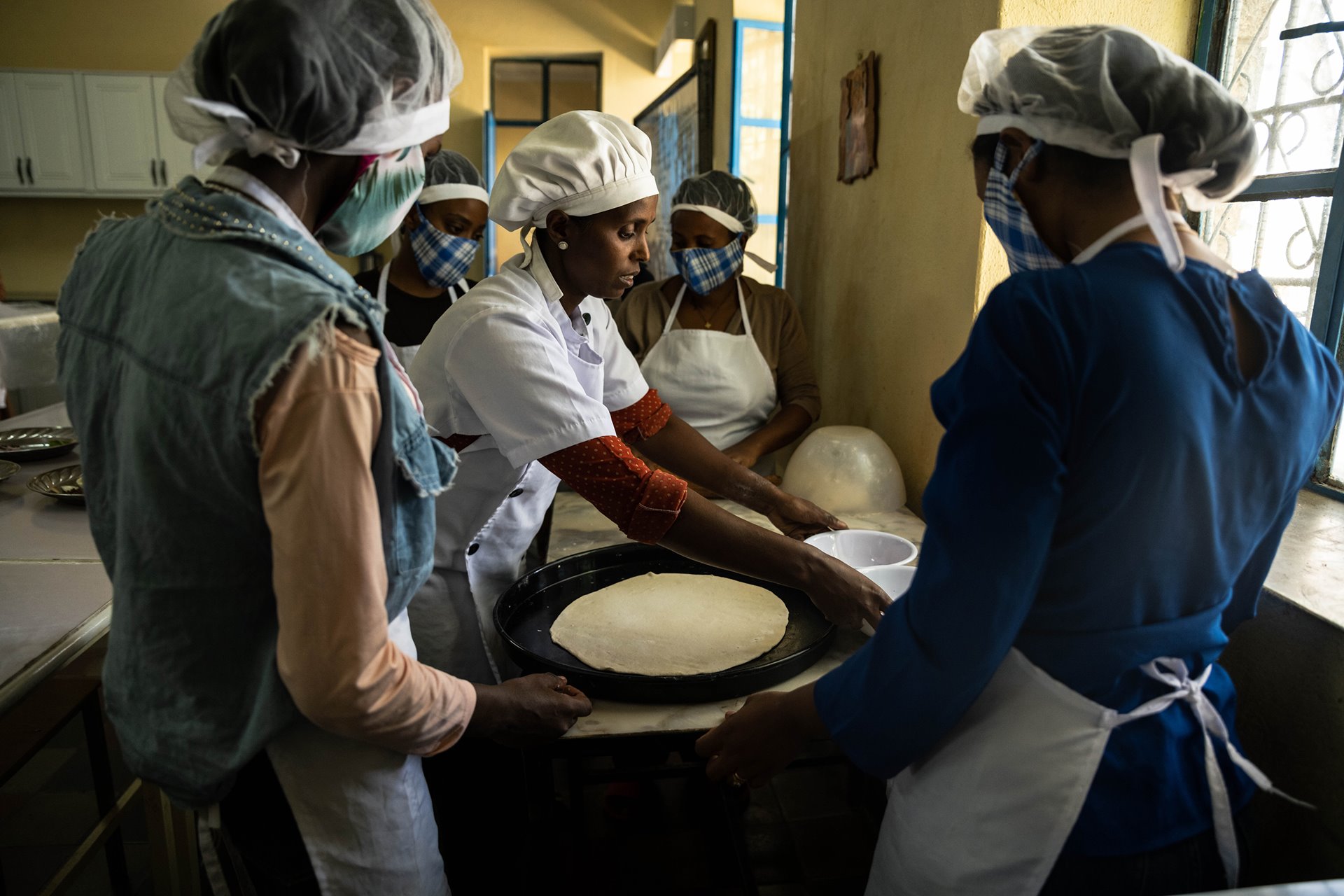 Bedla Salomon (center), cooking instructor, shows her students how to make pizza during a culinary class at the Daughters of Charity Training Center in Mekele, Ethiopia. The Daughters of Charity provide psychological support and job training to survivors of sexual violence.