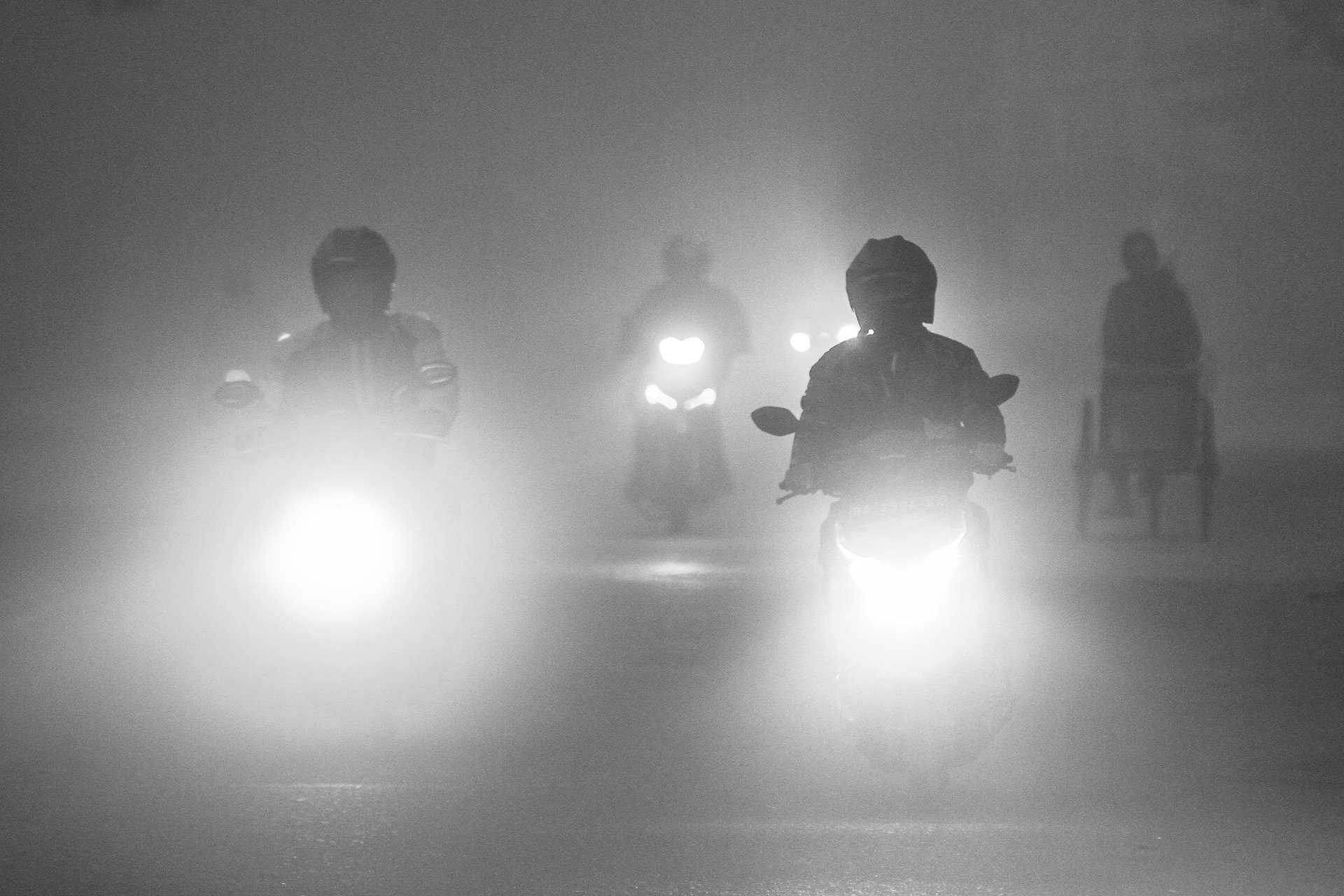 Motorcyclists in the city of Palembang, South Sumatra, Indonesia, ride through thick smoke that has drifted from a forest fire burning outside the city.