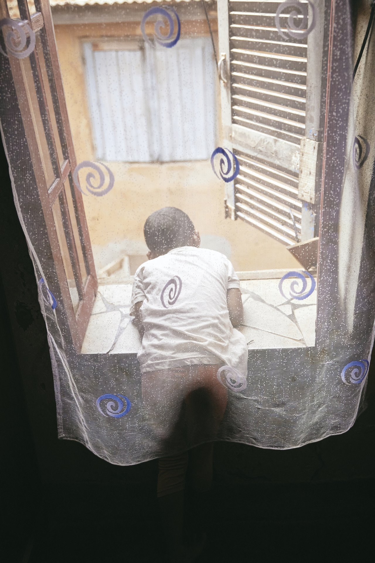 Odliatemix looks out the window of the bedroom she shares with her mother and grandfather, Dada Paul, in Antananarivo, Madagascar. She looks up to Dada Paul as a father figure, as her mother, Fara, is a single parent.