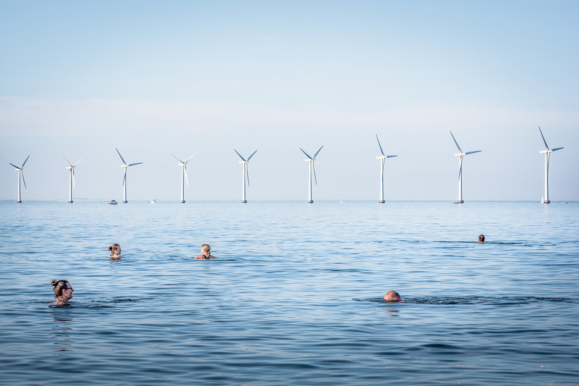 <p>People swim at Amager Strand, Denmark, near a wind farm which is co-owned by 8,552 electricity consumers, and serves more than 40,000 Copenhagen households. Upwards of 150,000 Danish families are members of similar wind-turbine cooperatives.</p>
