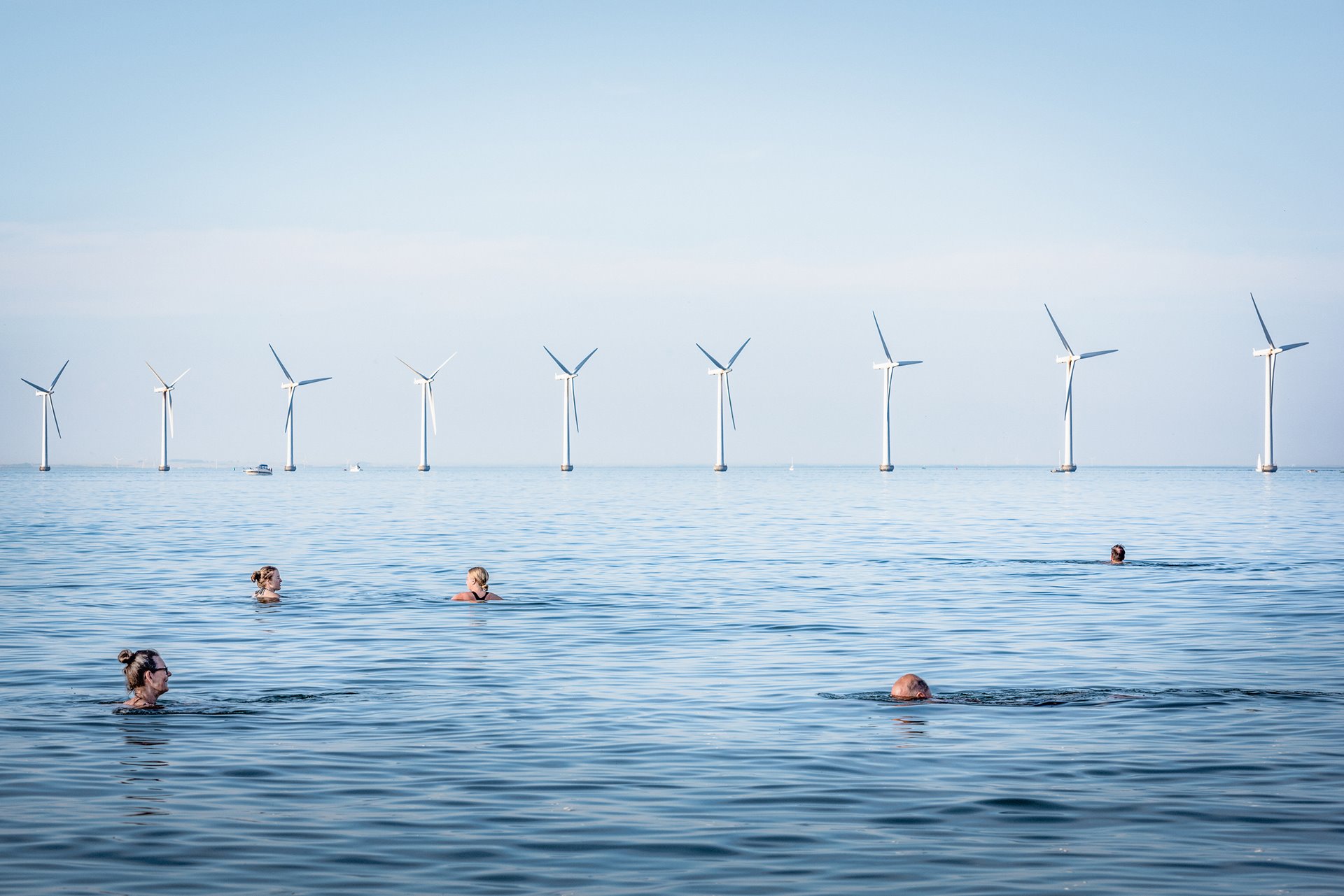 <p>People swim at Amager Strand, Denmark, near a wind farm which is co-owned by 8,552 electricity consumers, and serves more than 40,000 Copenhagen households. Upwards of 150,000 Danish families are members of similar wind-turbine cooperatives.</p>
