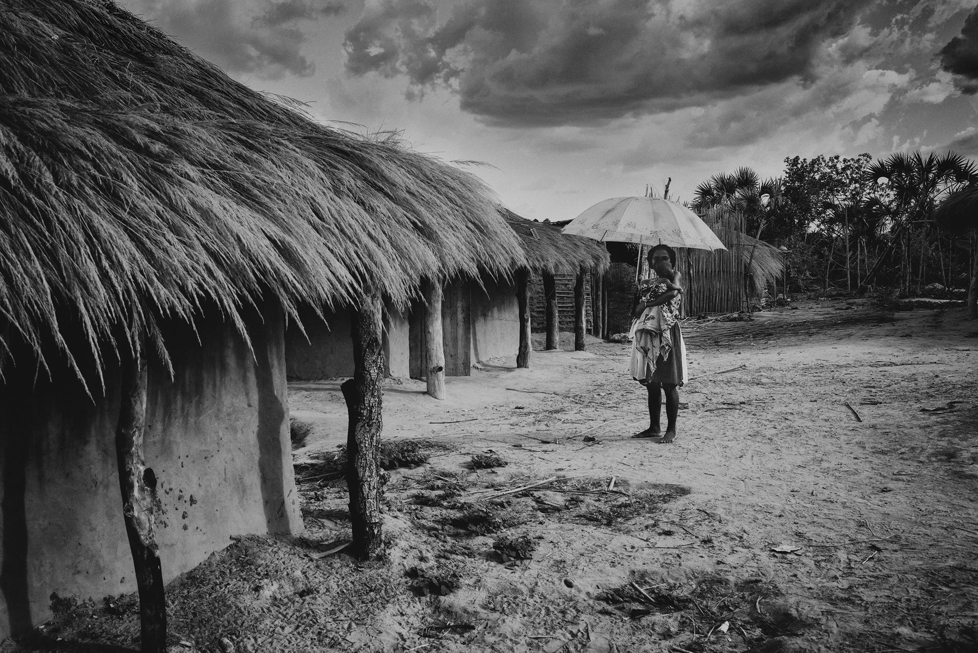 A woman protects her son from the sun with the help of an umbrella, in the village of Mataviakoho, in Menabe, west-central Madagascar. The village is reputed to be the base of the notorious head of a group of <em>dahalo</em> cattle thieves.