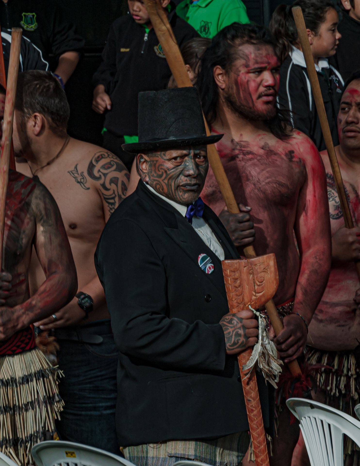 Tāme Iti, a prominent Tūhoe artist and activist bearing a tā moko (traditional facial tattoo), stands at the 2014 Tūhoe-Crown Settlement Day ceremony in Tāneatua, New Zealand, where the government formally apologized for historical injustices. Iti&#39;s tā moko helped shift perception of the tattoos in the 1970s and 1980s from gang associations to a symbol of Māori pride. The intricate designs represent his lineage and tribal connections.