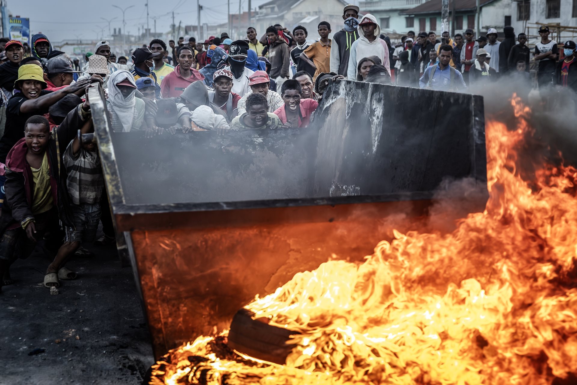 Protesters push a metal container forward as a barricade during clashes with Malagasy security forces in Antananarivo, Madagascar. The same day, President Rajoelina agreed to speak directly with protest leaders. They refused his offer.&nbsp;