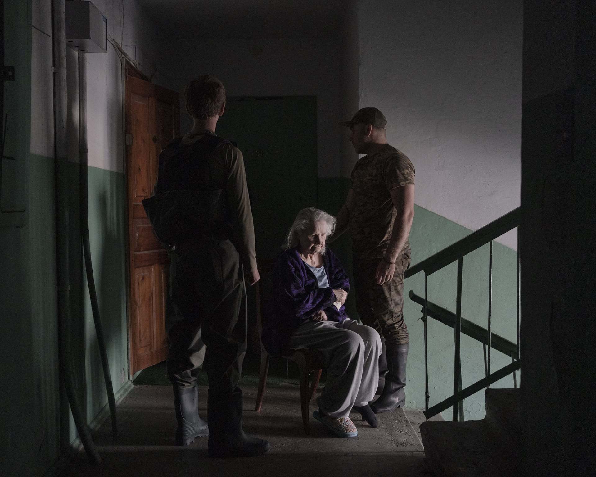 Viktor and Yevhen carry Maria from her 9th-floor apartment for evacuation by boat in Kherson, Ukraine.