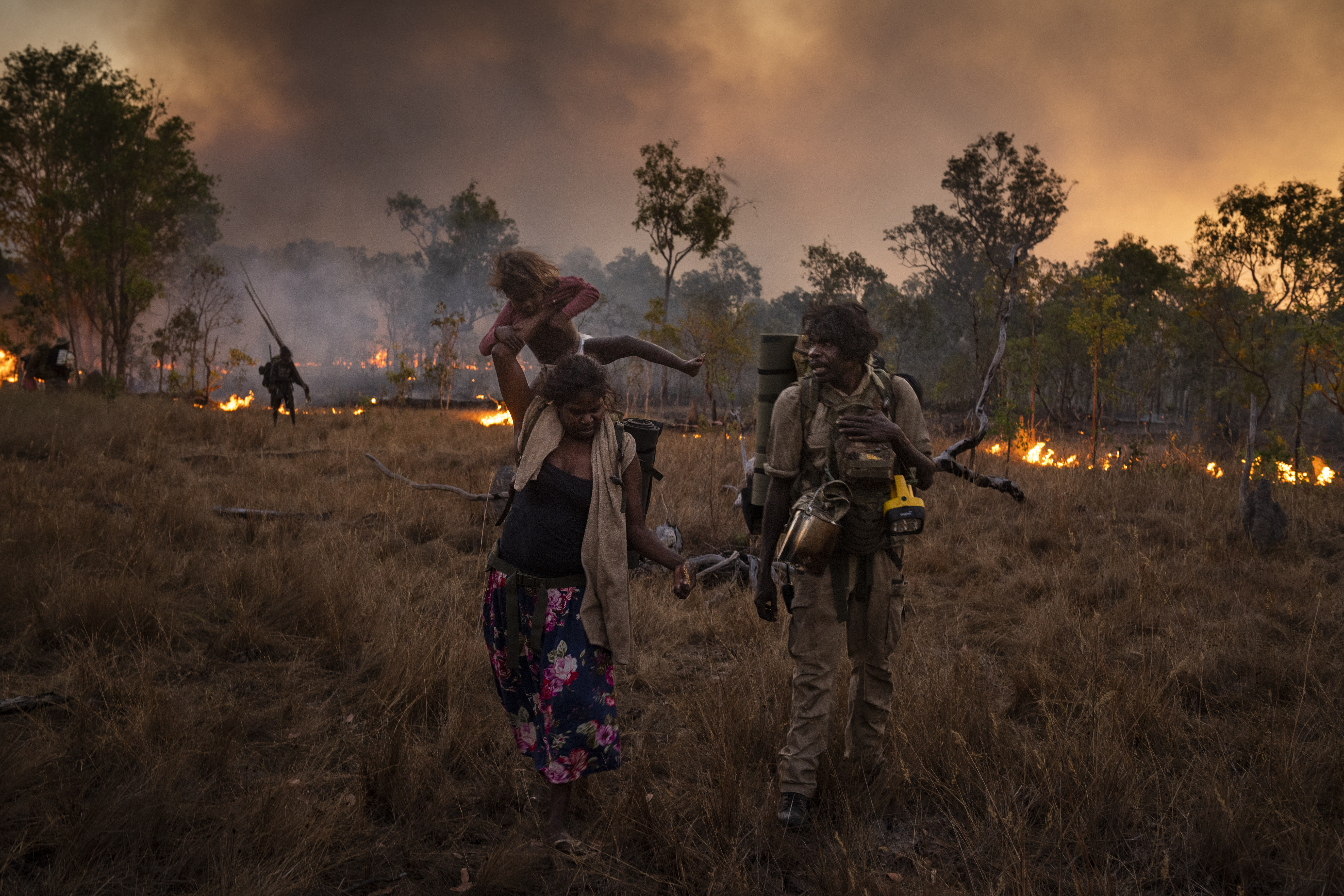 During a five-day bushwalk across several clan estates early in the dry season, a family follows a fire lit by other members of the clan, to help guide them on their journey and to clear the land to prevent destructive fires.