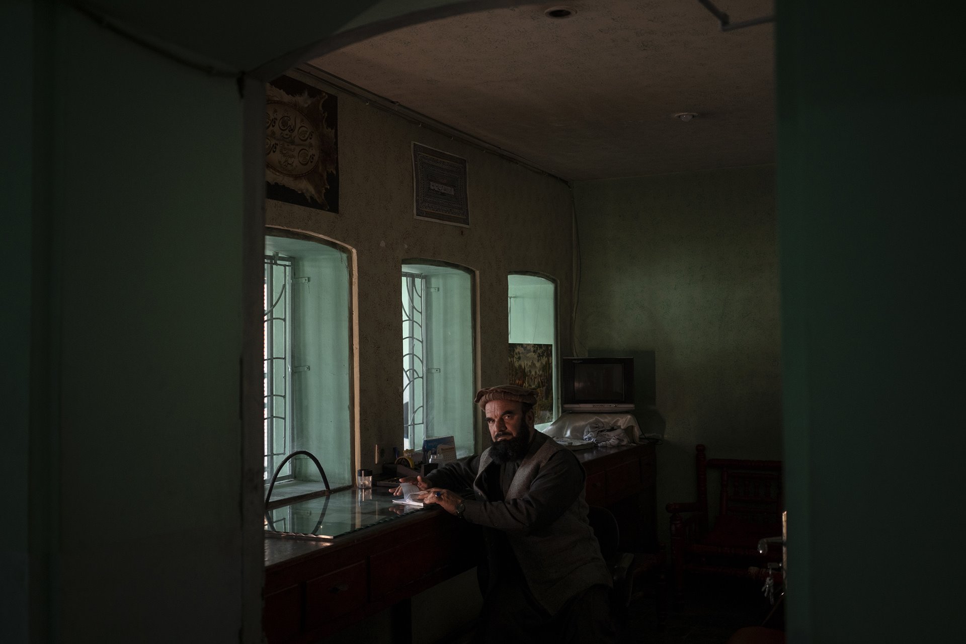 Abdul Malik Wahidi, who sells tickets at Ariana Cinema, in Kabul, Afghanistan, poses for a photograph in the ticket office. Nearly three months after the Taliban closed the government-owned cinema, the staff still arrive for work in the hope that they will be paid.