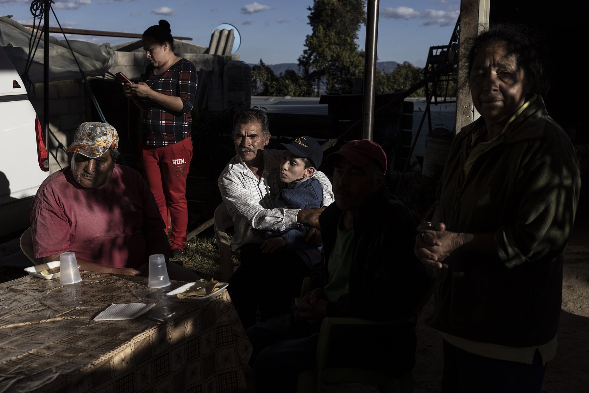 <p>Don Tino holds his son Sebastián (18), who lives with hydrocephalus (a neurological disorder caused by a build-up of fluids in cavities within the brain), at a family reunion, in Villa Guerrero, Mexico. Carmelita (16, not pictured), the daughter of the hosts, lives with encephalomalacia (softening of the brain tissue), Marisela (looking at cell phone, also a relative) has experienced two stillbirths, and other family members live with conditions possibly linked to agrichemicals.</p>
