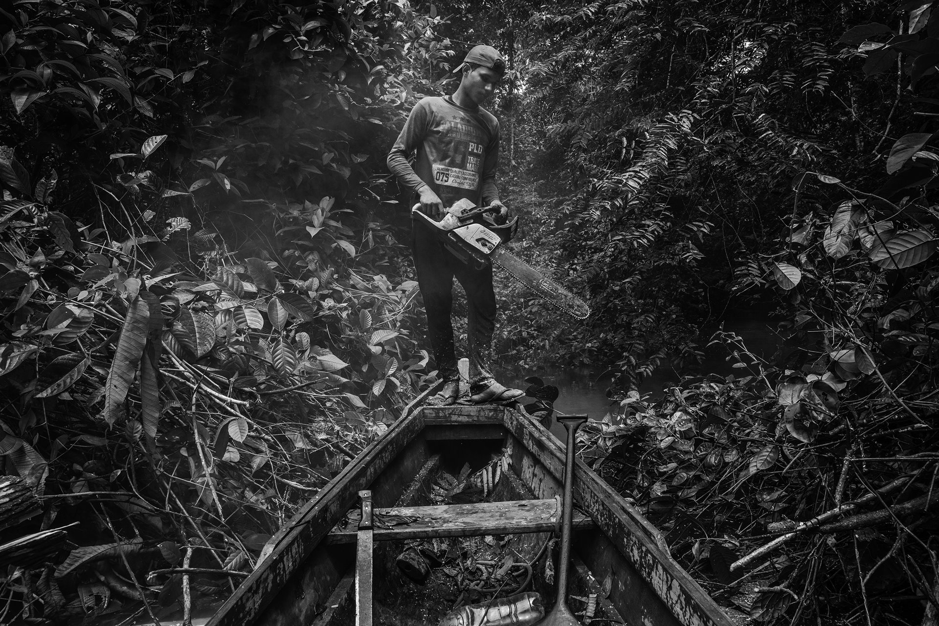 Jasson Oliveira do Nascimento, a resident of the Arapixi Extractive Reserve in the Brazilian Amazon, uses a chainsaw to clear a path for his canoe on his way to collect Brazil nuts. The reserve was established in 2006 as a protected area with sustainable use of natural resources, to safeguard livelihoods and culture of the traditional extractive population. The aim was to protect the area against large-scale soybean farming and cattle ranching, but it is currently being invaded by land-grabbers, who are deforesting the jungle and threatening the way of life of the 300 families who live there.