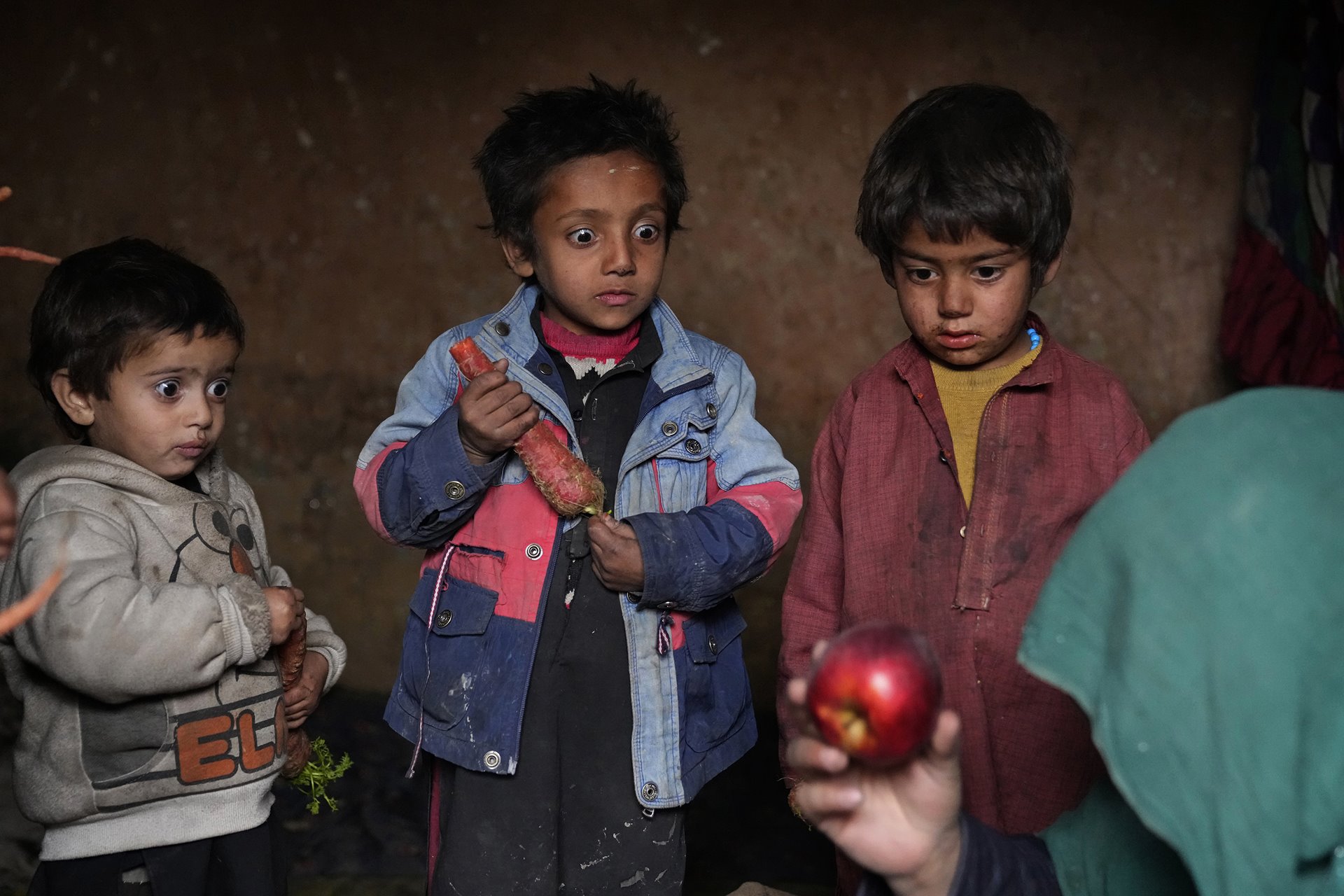 Children stare at an apple that their mother brought home after begging, in a camp for internally displaced people in Bagrami, on the outskirts of Kabul, Afghanistan.