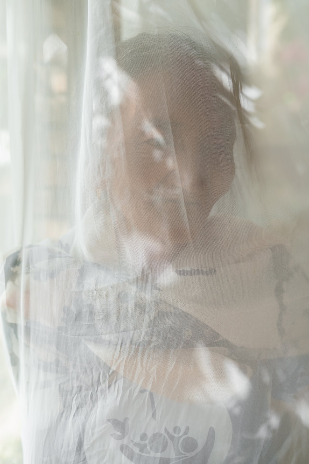 Maria stands behind a curtain for a portrait, during a grief counseling retreat in Tagaytay, in the Philippines. Maria&rsquo;s grandson Andrew, who worked as a repairman and was the provider for her and her younger grandchildren, was killed in 2016. After Andrew was killed, Maria said she would sometimes find bullets outside her house, making her afraid. &nbsp;She agreed to participate in this story only if her image were obscured and names changed, for fear of repercussions for speaking out. In August 2021, Maria died in her sleep.&nbsp;