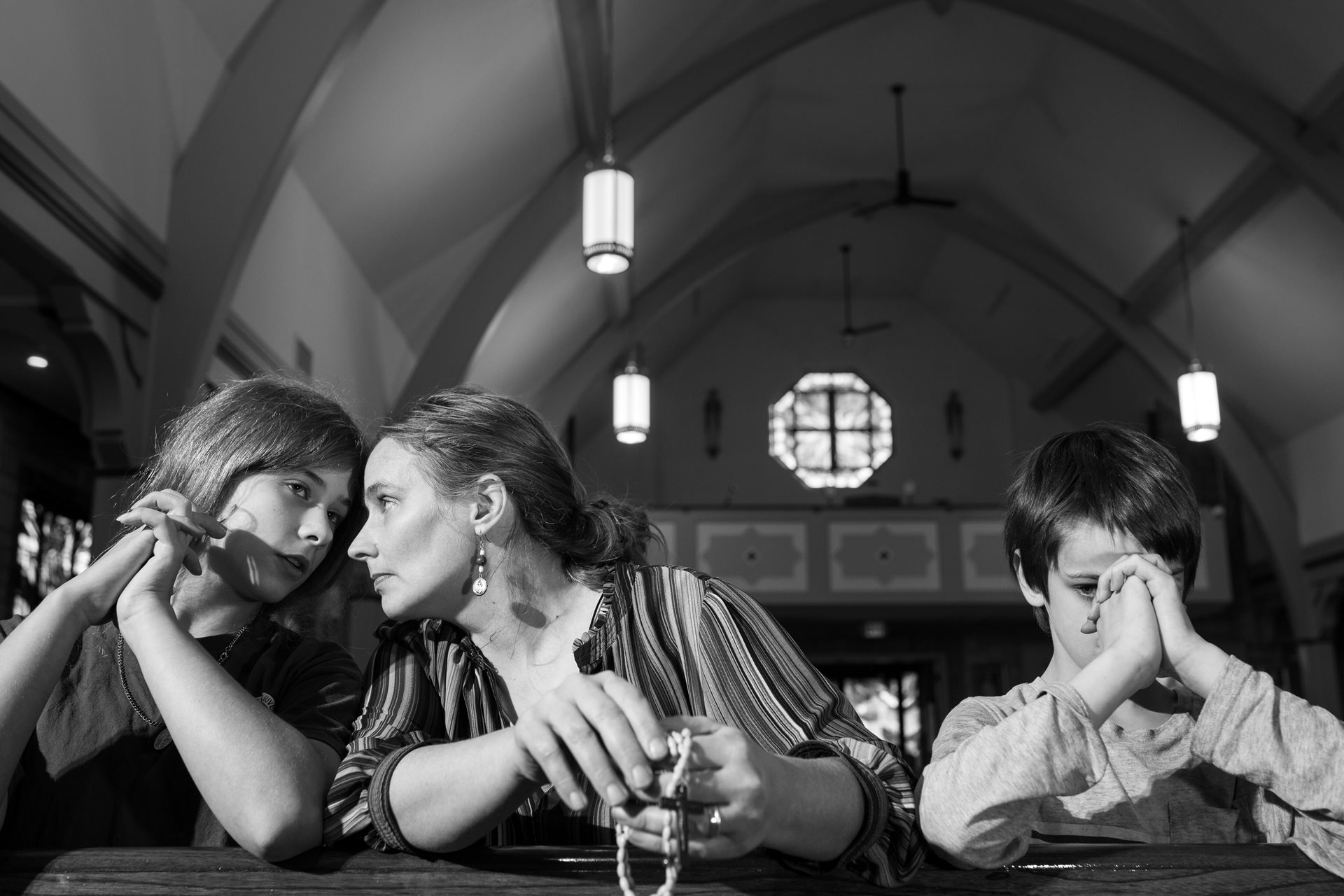 Maria, Robin, and Joseph Seman pray at Our Lady of Lourdes Parish on the anniversary of the Norfolk Southern train derailment. Many members of Robin Seman&rsquo;s family experienced health issues after the derailment. Seman homeschools her children. During one lesson about the derailment, Seman posed the question, &quot;How do we fix this, for our community, for our neighbors?&quot; Maria replied, &quot;We pray.&quot; Seman then asked, &quot;What are we called to do with our prayers?&quot; Maria replied, &quot;We act.&rdquo; East Palestine, Ohio, United States.
