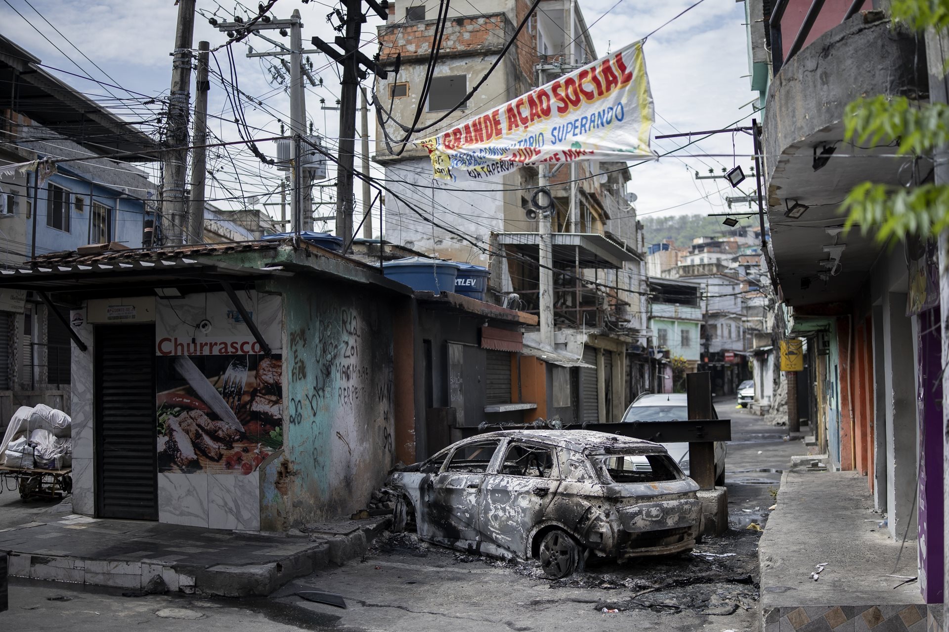 A vehicle burned by drug traffickers smolders at a barricade, hindering police access to the Penha complex, in&nbsp;Rio de Janeiro, Brazil. Setting vehicles ablaze is a common tactic to delay advancing law enforcement.&nbsp;