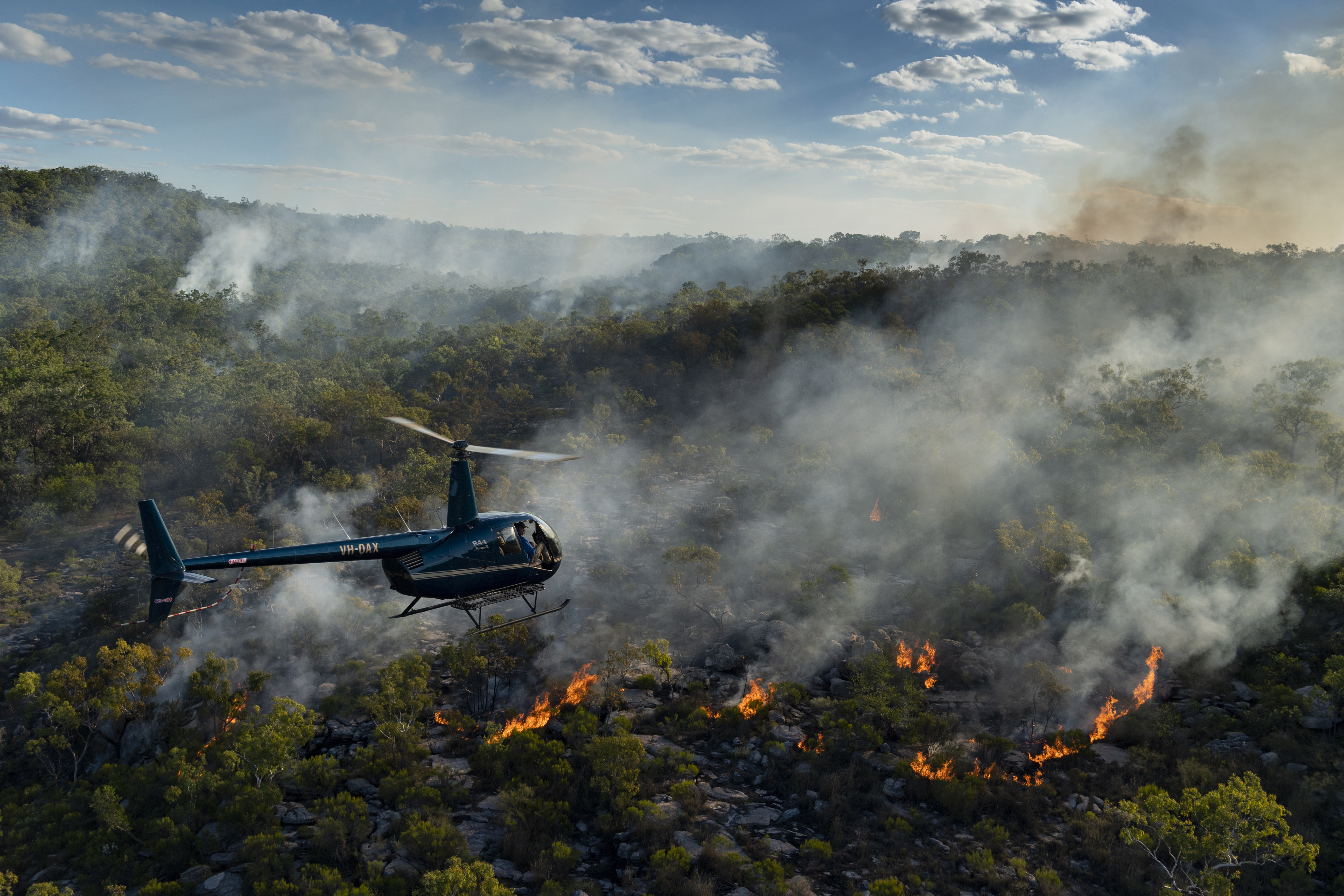 A helicopter drops fireballs the size of ping-pong balls to create small fires, in a controlled burning operation in Capari country, Arnhem Land, Australia.