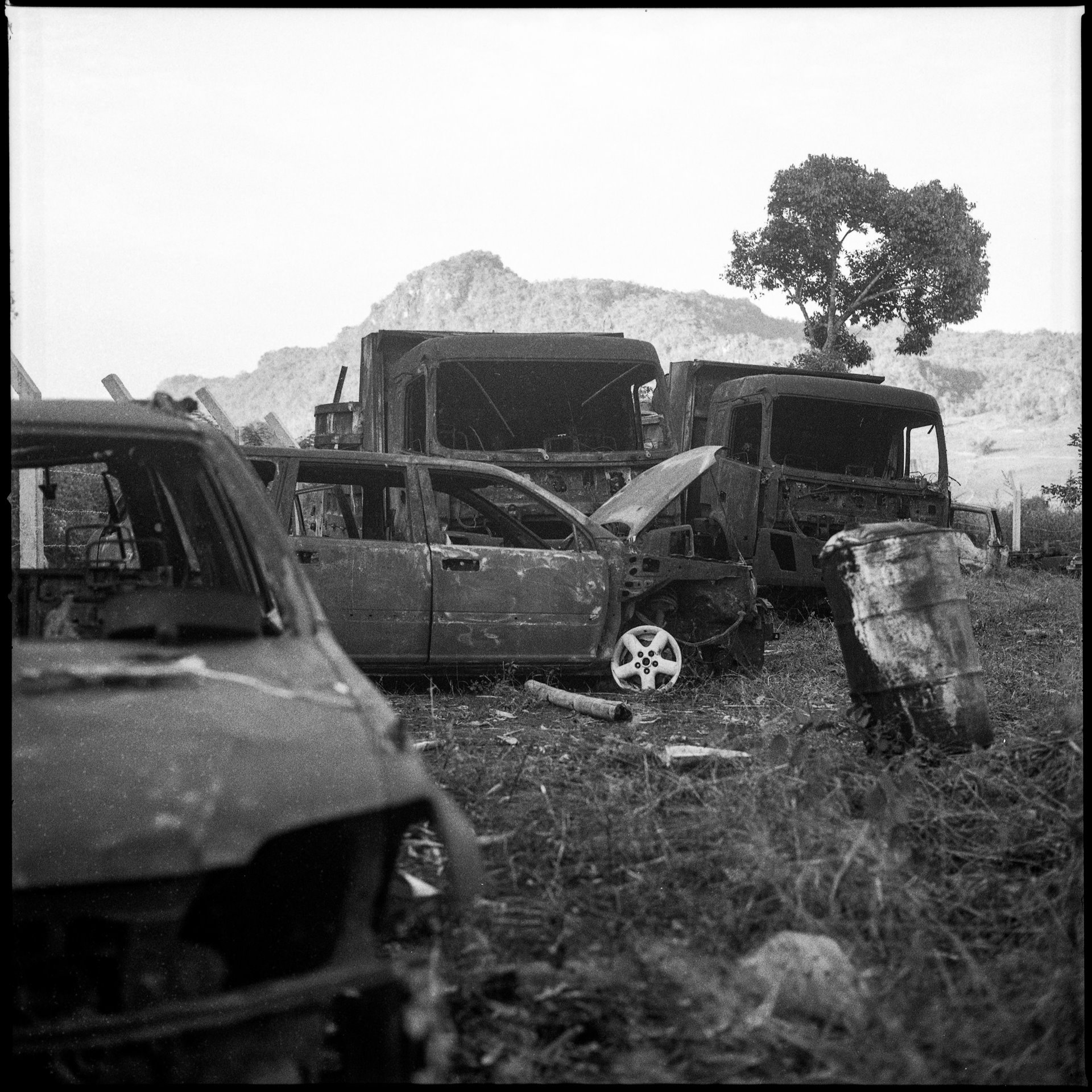Derelict vehicles still stand near Mo So, Kayah (Karenni) State, Myanmar, a year after they were found burnt outside the village. According to state media, the drivers had refused to stop at a checkpoint. A villager told Associated Press the victims had been fleeing fighting and heading to a refugee camp. Over 30 bodies were found, including two Save the Children staff members.