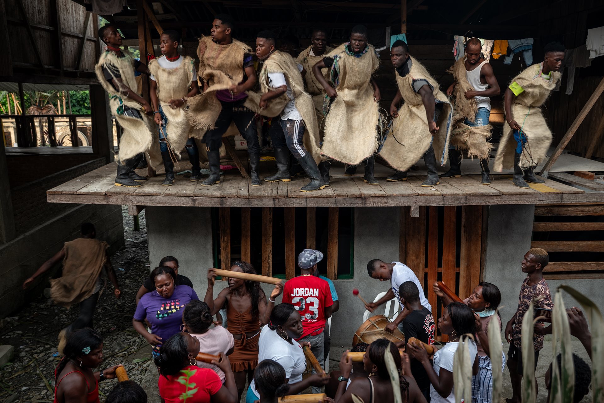 Jhony (sixth from left) leads the Manacillos through Juntas, Buenaventura, Colombia. The dancers visit every house to ask for protection and reconnect with the diaspora. For five days, displaced families return to the river to reaffirm their community bonds.