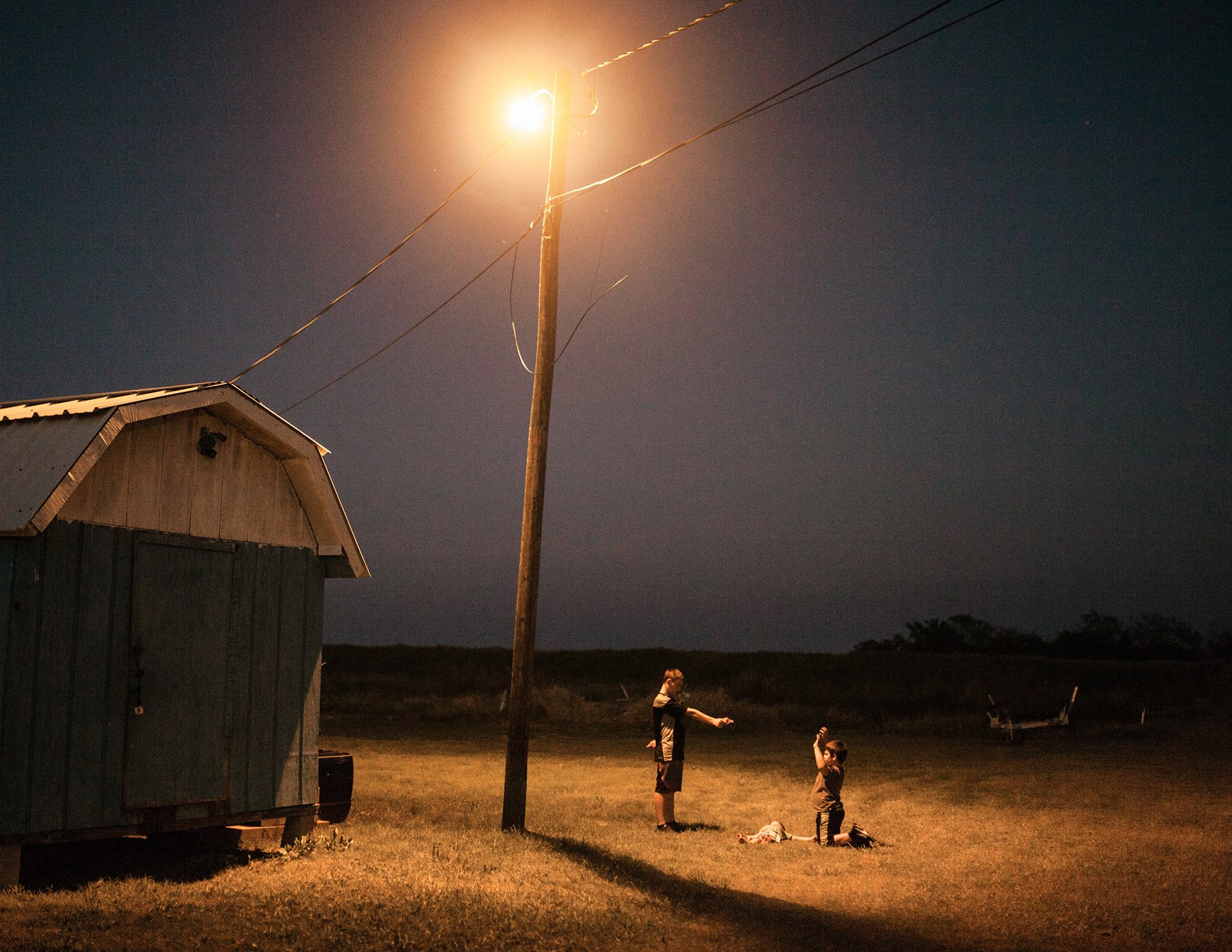 Cage and his two younger brothers play with plastic guns behind the house of their grandfather, Hilton Chaisson in Isle de Jean-Charles, in southeastern Louisiana, United States. At that time, there were less than a dozen teenagers left on the island. Chaisson&rsquo;s house has already been rebuilt thirteen times, due to previous hurricanes and floods.&nbsp;