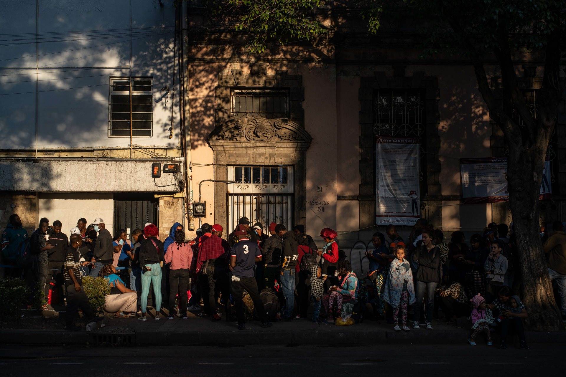 Migrants stand in line outside an office in Mexico City, seeking a refugee card that will enable them to use public transportation for their journey north. This card is essential for them to travel within Mexico as they make their way to the border with the United States. Mexico City, Mexico.