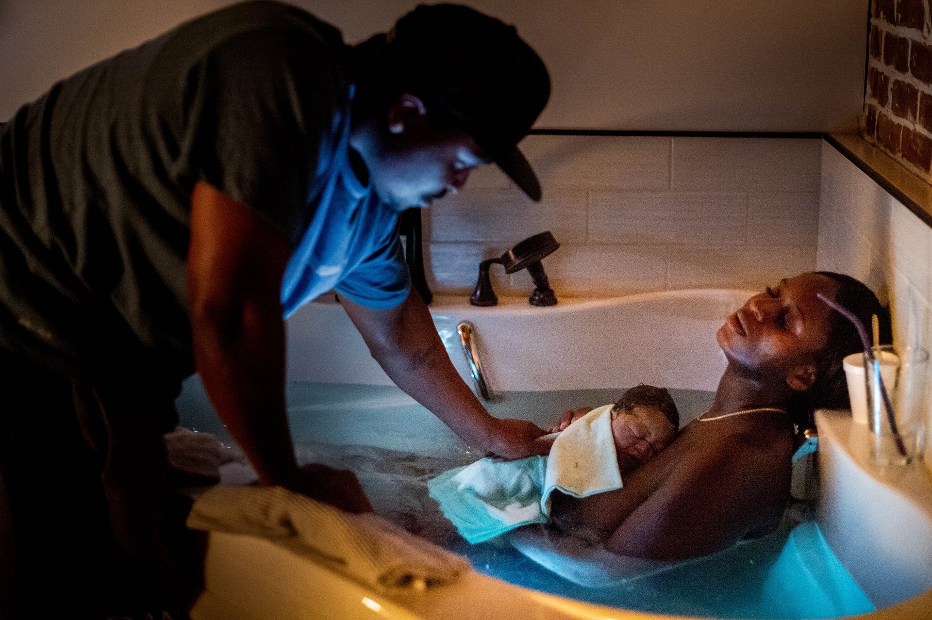 While Aysha rests, her partner Dennis Richmond touches their son after catching their baby in the birthing bath at the Kindred Space LA birthing center, in South Los Angeles, USA, on Mothers&rsquo; Day.