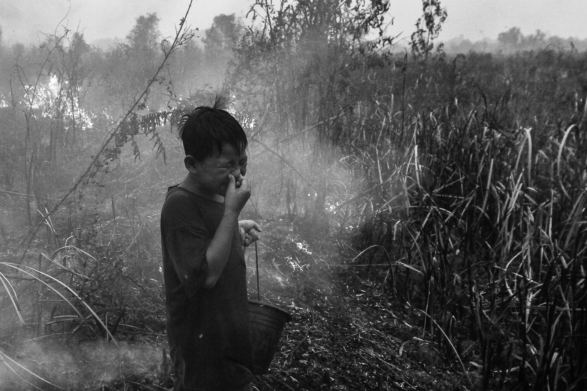 <p>A boy reacts to stinging smoke from a peatland fire in Ogan Ilir, South Sumatra, Indonesia.</p>
