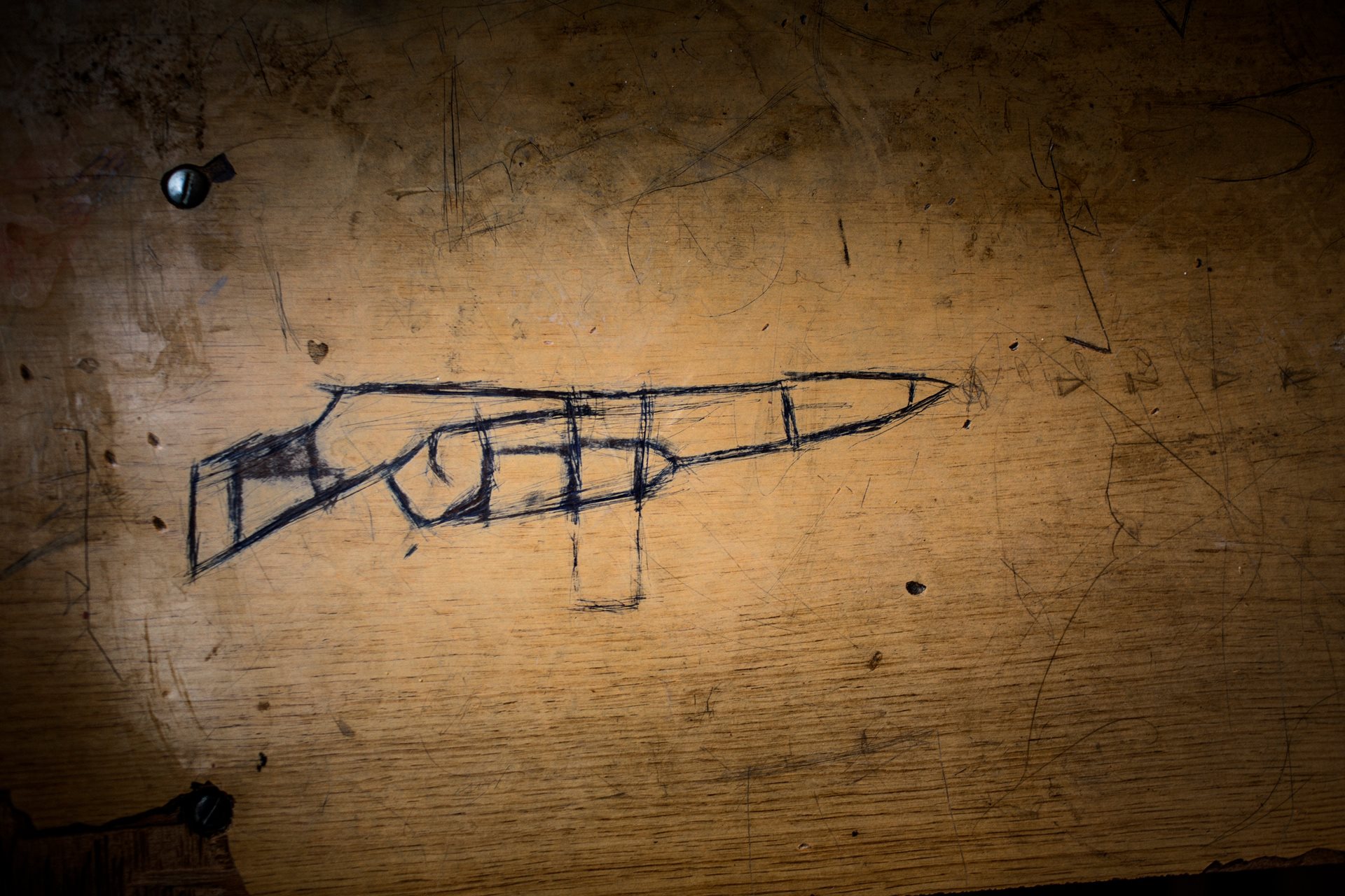 A drawing of a machine gun on a desk at Hajj Ali High School for boys in Hajj Ali, Iraq, taken over as a shelter during conflict.