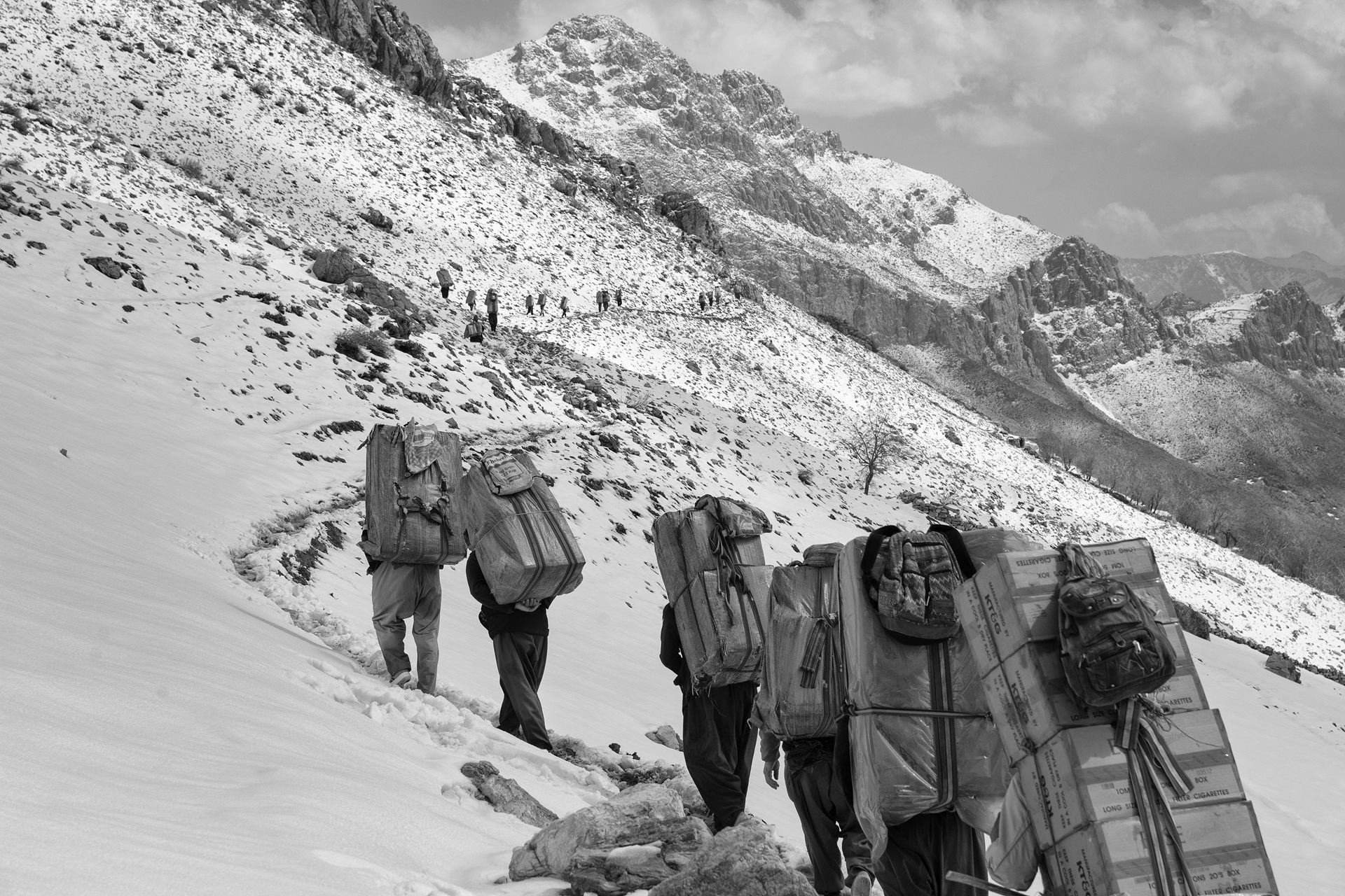 Kolbars make their way along a mountain pass between Iran and Iraq, in Kurdistan, Iran.