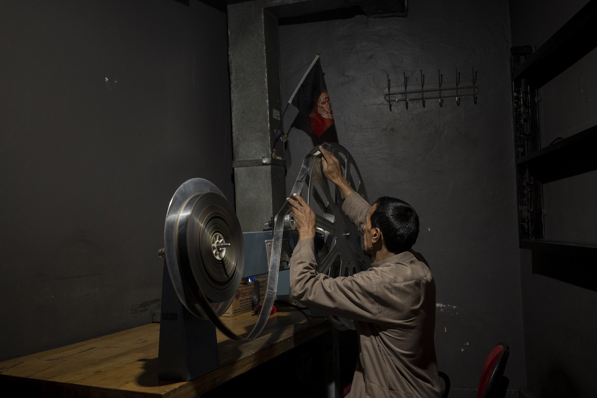 Rahmatullah Ezati inspects a roll of film for damage, in the projection room of the Ariana Cinema in Kabul, Afghanistan. Even though the Taliban closed the government-owned cinema a few months earlier, the staff still arrive for work daily, in the hope they will eventually be paid.