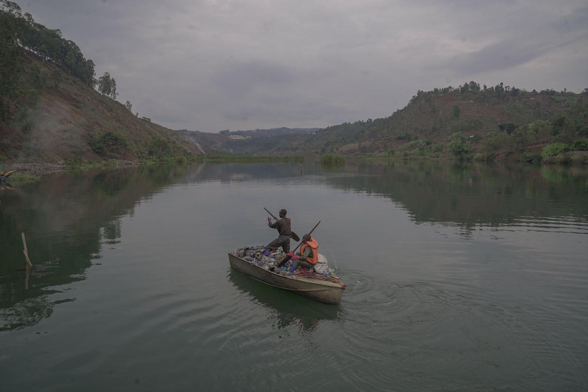 Two people in a small boat collect plastic waste from the Ruzizi River in Bukavu, DRC.