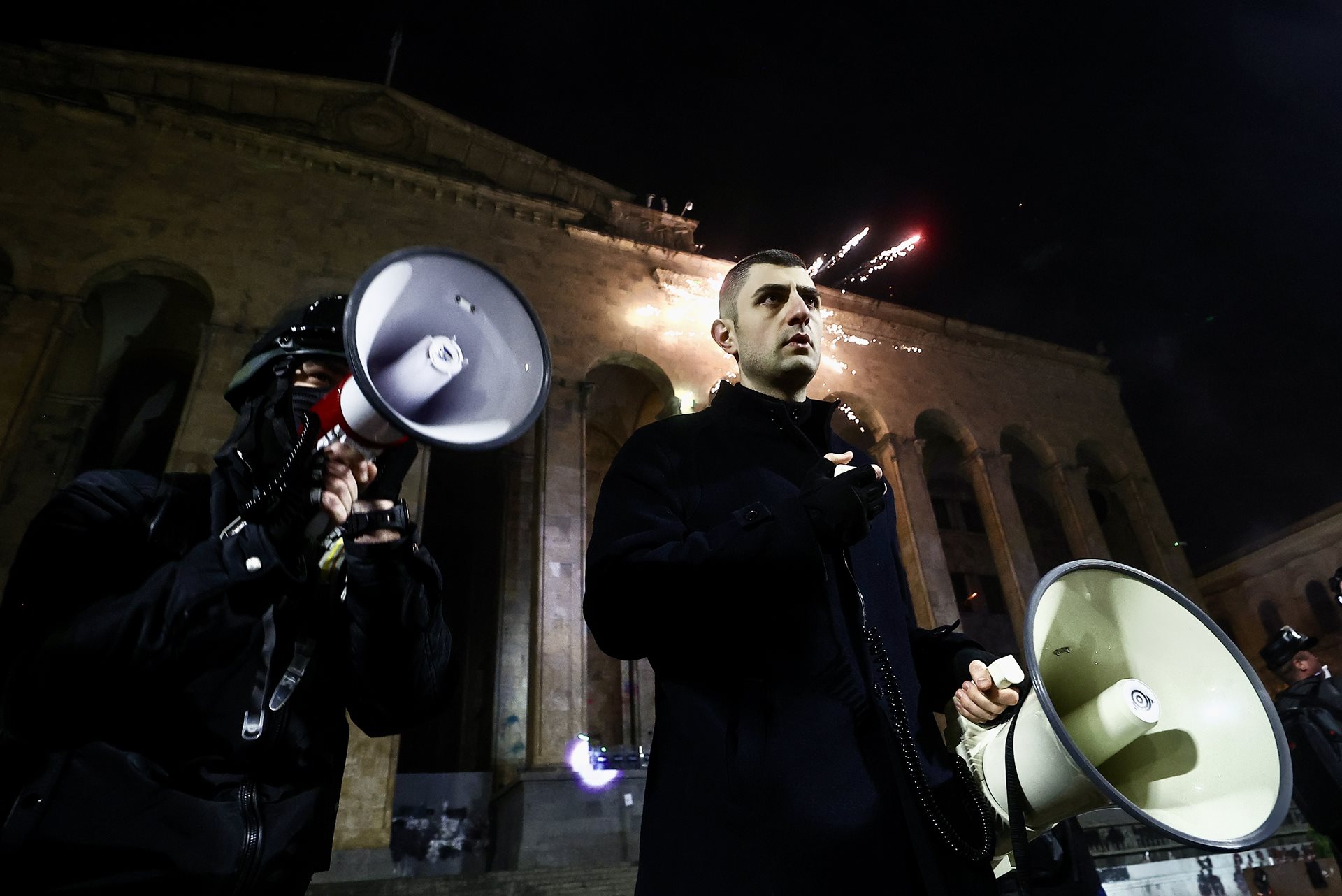 Protesters shout anti-government slogans during a rally outside the Parliament of Georgia, while others launch fireworks from atop the Georgian Museum of Fine Arts, in Tbilisi.