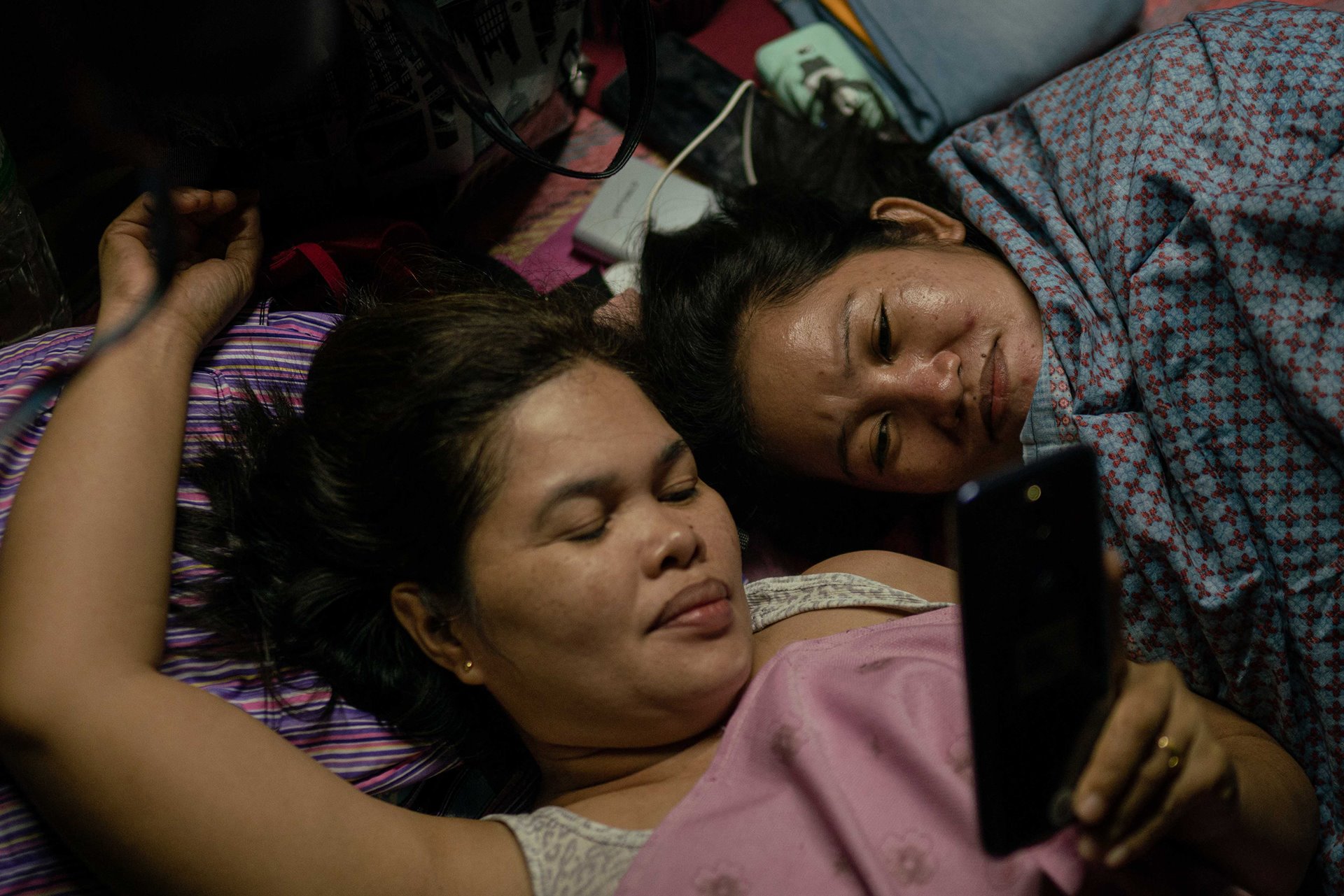 Marilyn Malimban and Jenny Tiaga watch a video on Marilyn&#39;s phone during a hike and camping trip in &nbsp;Mount Banahaw in Quezon Province, the Philippines. Both lost their husbands to the war on drugs and had to work away from home to support their children.The hike was organized by Paghilom (Healing), a program started in 2016 by former drug user Father Flaviano Villanueva for families of victims of the war on drugs, providing them with support and counseling.&nbsp;