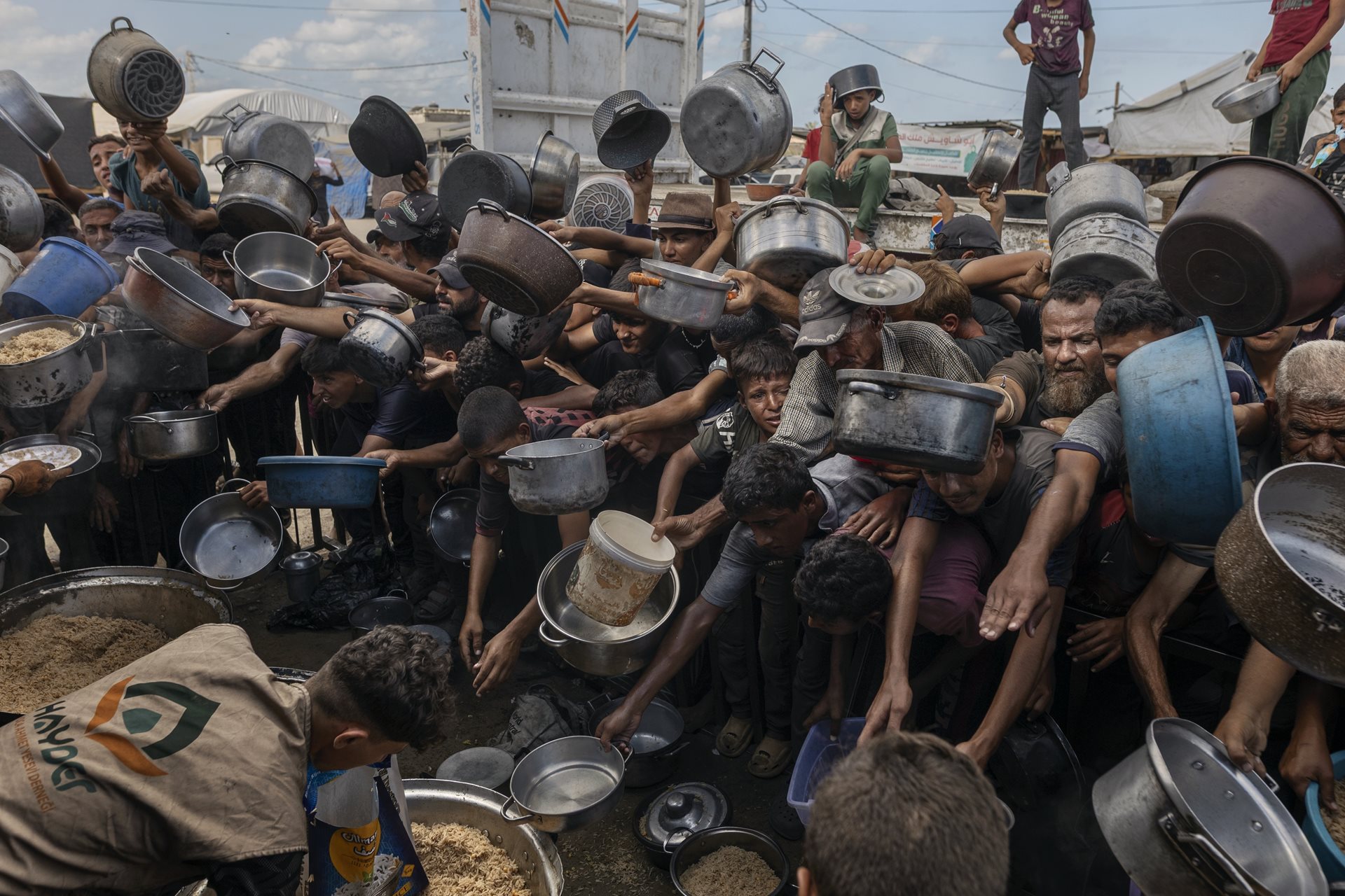 Palestinians at Al-Mawasi displacement camp in Khan Younis, Gaza Strip, wait for a meal. Local charity kitchens were one of the only food sources for many of Gaza&rsquo;s displaced.