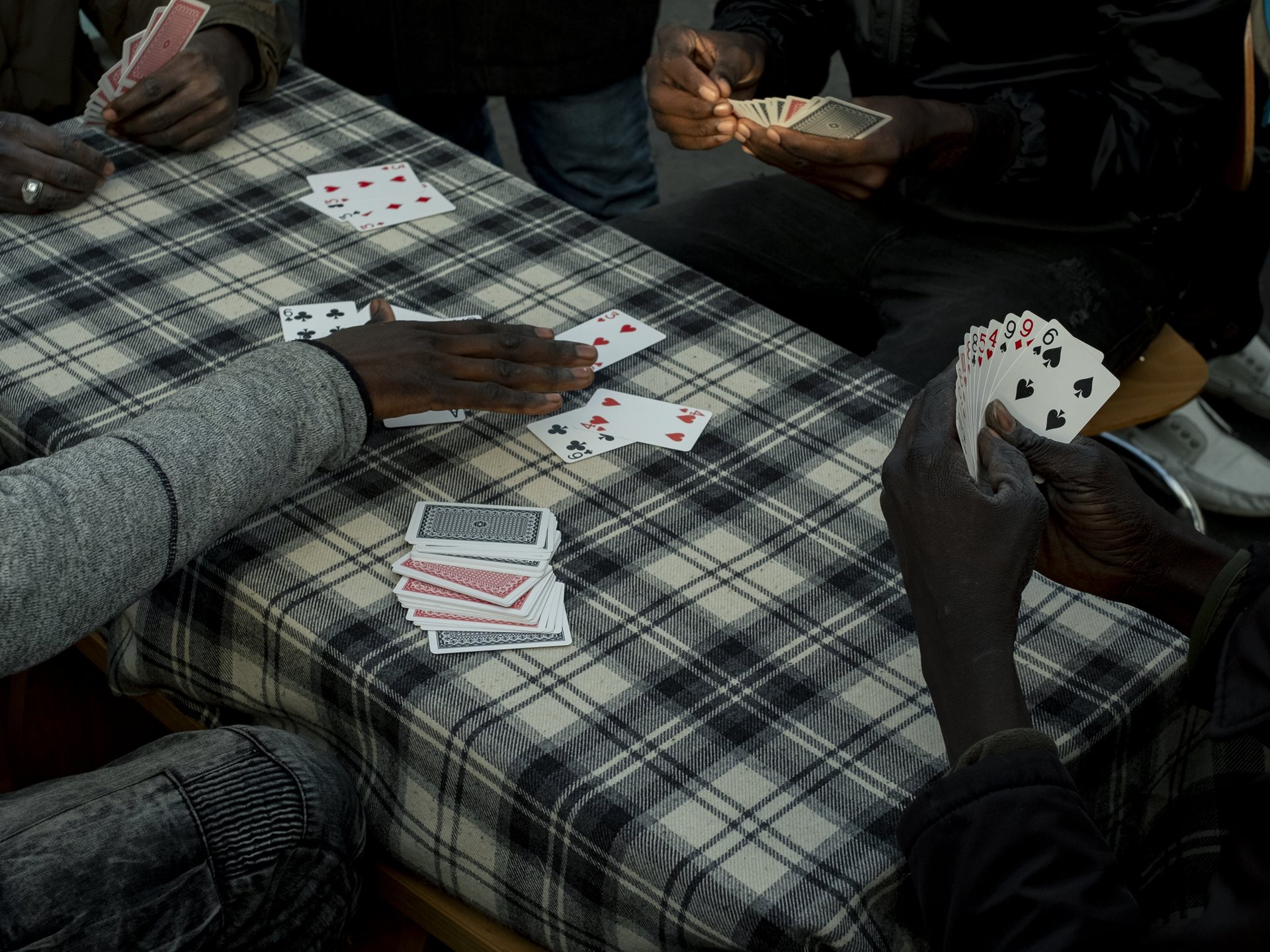 <p>​​Sudanese migrants spend the afternoon playing cards at the Ecluse camp, an unofficial settlement opposite the Stade de France. Saint-Denis, France</p>
