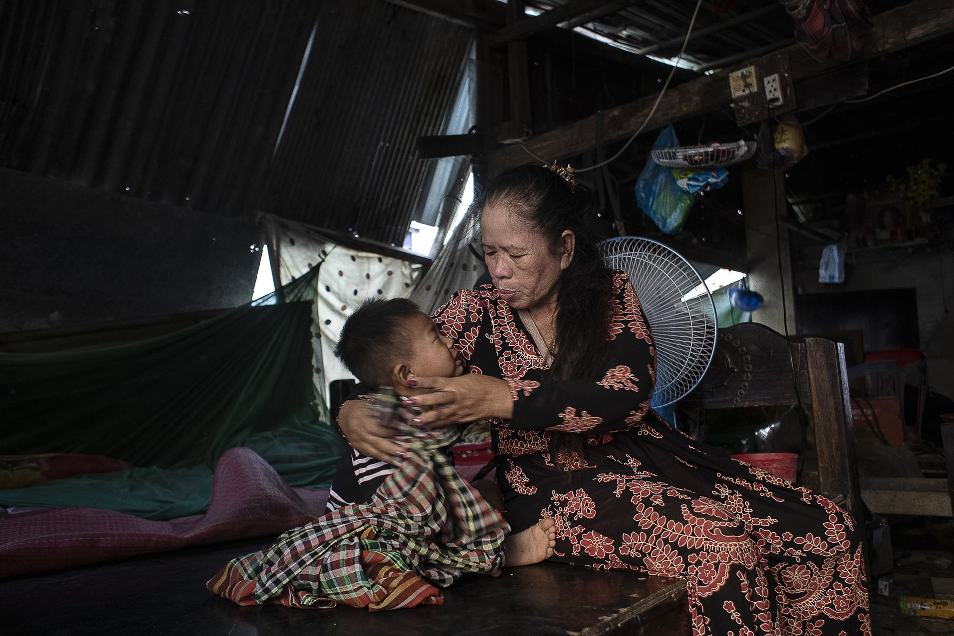 <p>Chandarayoth Pheap (3) is comforted by his grandmother, Bonan Ky, at his surrogate mother Sreyroth&rsquo;s home in Phnom Penh, Cambodia. His grandmother takes care of him while both his parents work.</p>
