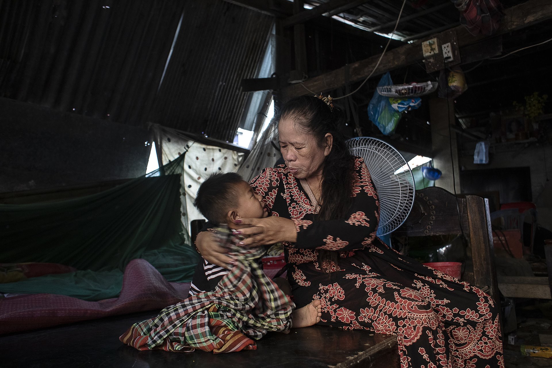 <p>Chandarayoth Pheap (3) is comforted by his grandmother, Bonan Ky, at his surrogate mother Sreyroth&rsquo;s home in Phnom Penh, Cambodia. His grandmother takes care of him while both his parents work.</p>
