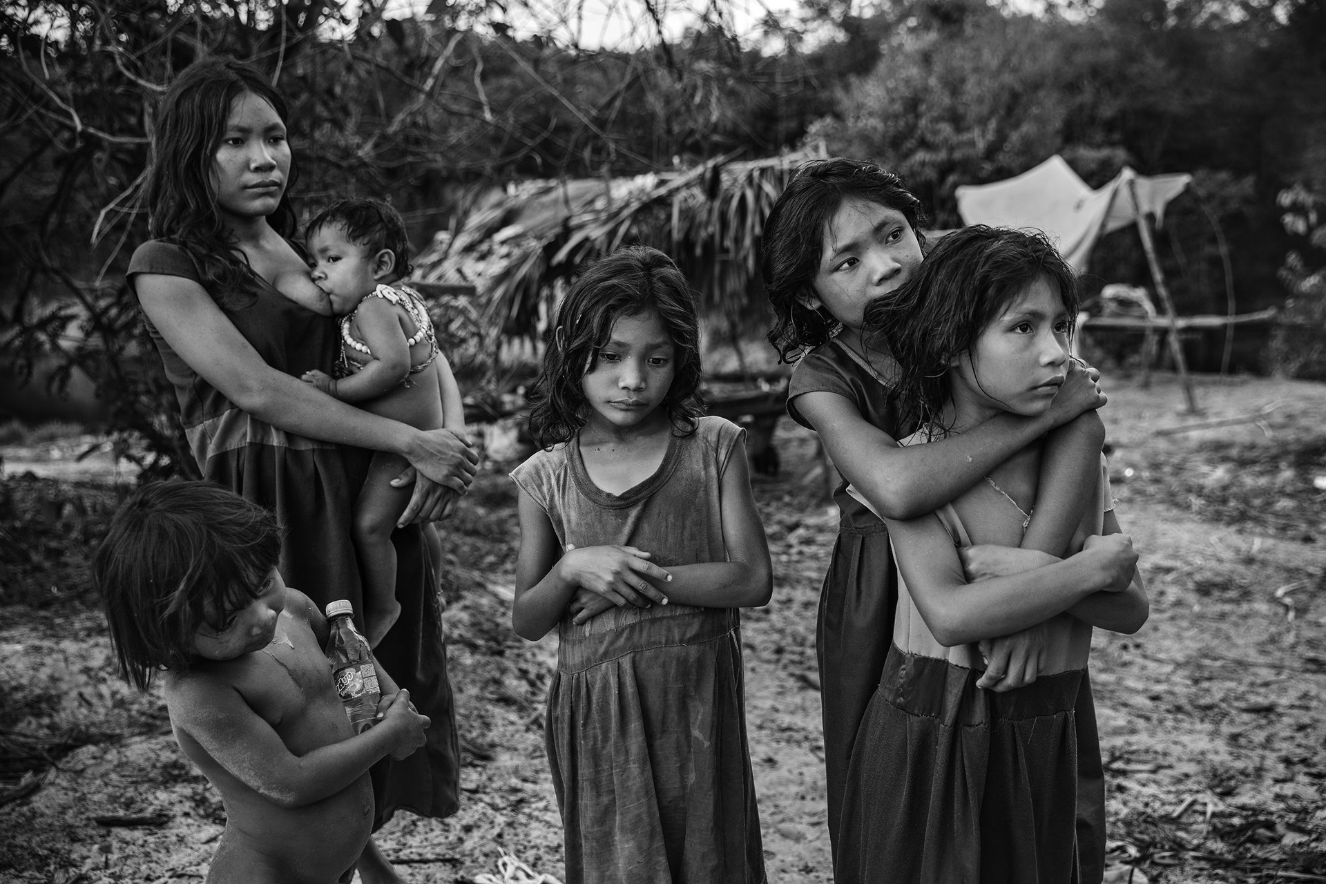 <p>Women and children from the Pirahã community, standing next to their camp on the banks of the Maici River, watch drivers passing by on the Trans-Amazonian highway hoping to be given snacks or soft drinks, Humaitá, Amazon, Brazil.</p>
