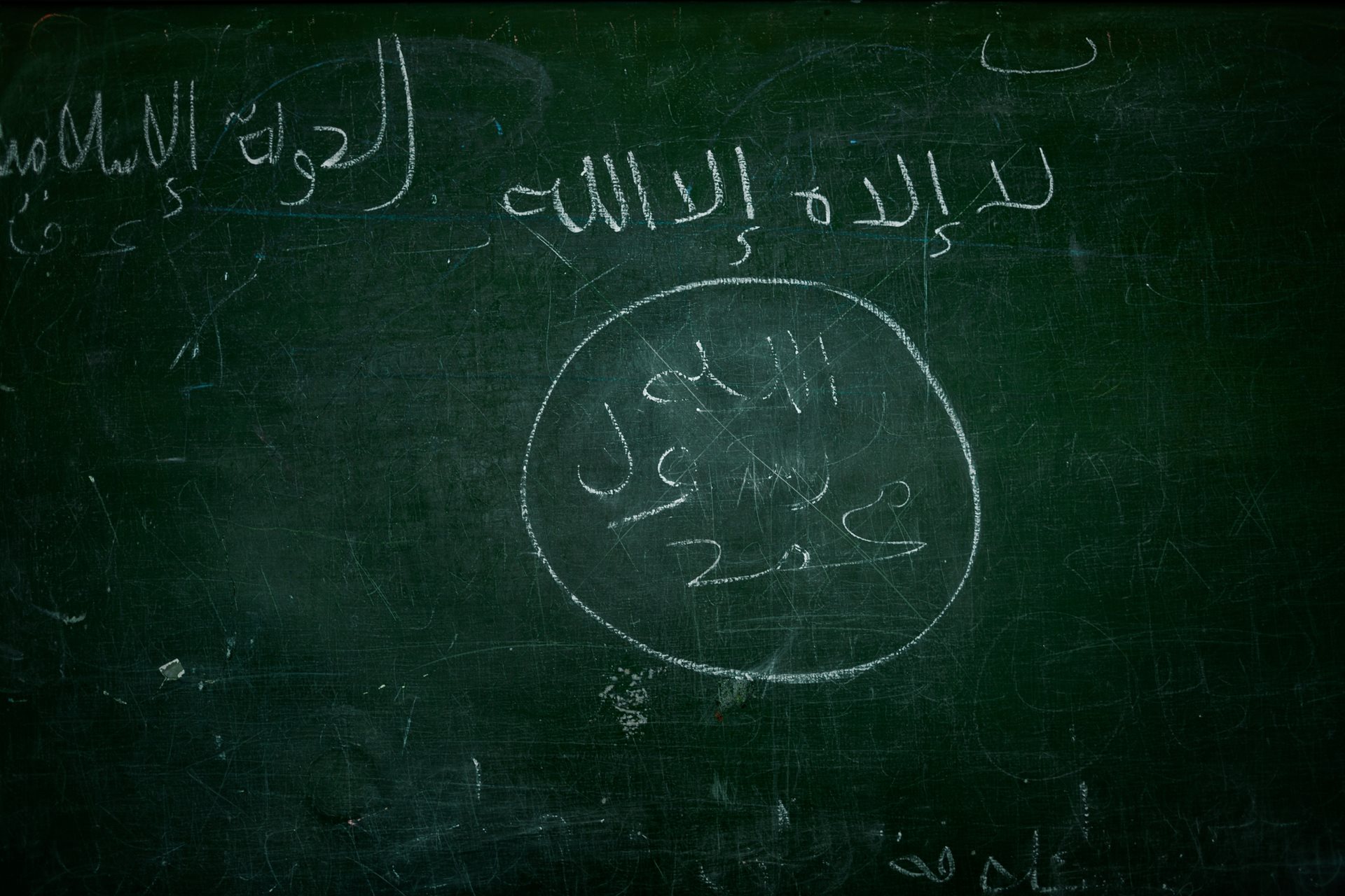 A classroom blackboard with a drawing of the flag used by ISIS militants, found inside a destroyed school in Al-Shaddadi, Syria. Education restarted in Al-Shaddadi in January 2026 after a decade-long suspension.