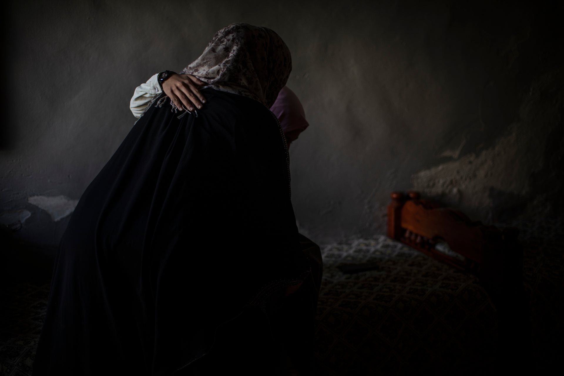 Dalia Mohammed Fathi (17) is helped by her mother to sit on a bed at their home in Mosul, Iraq. An explosion at a local market killed her father instantly and left Dalia with a spinal injury; she remained unconscious for two months.
