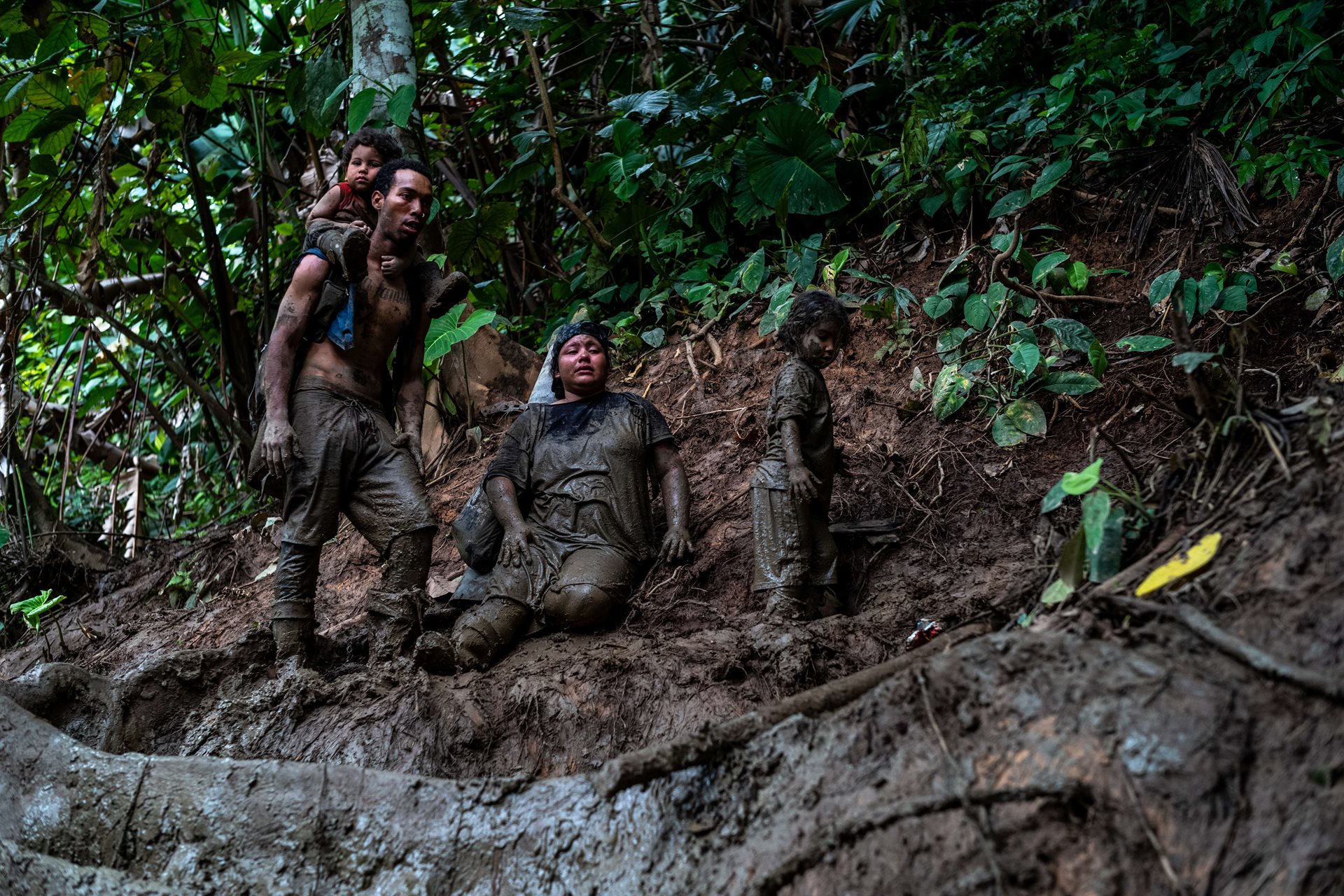 Beryomar Alexander Lopez and his family are covered in mud as they navigate the Darién Gap.