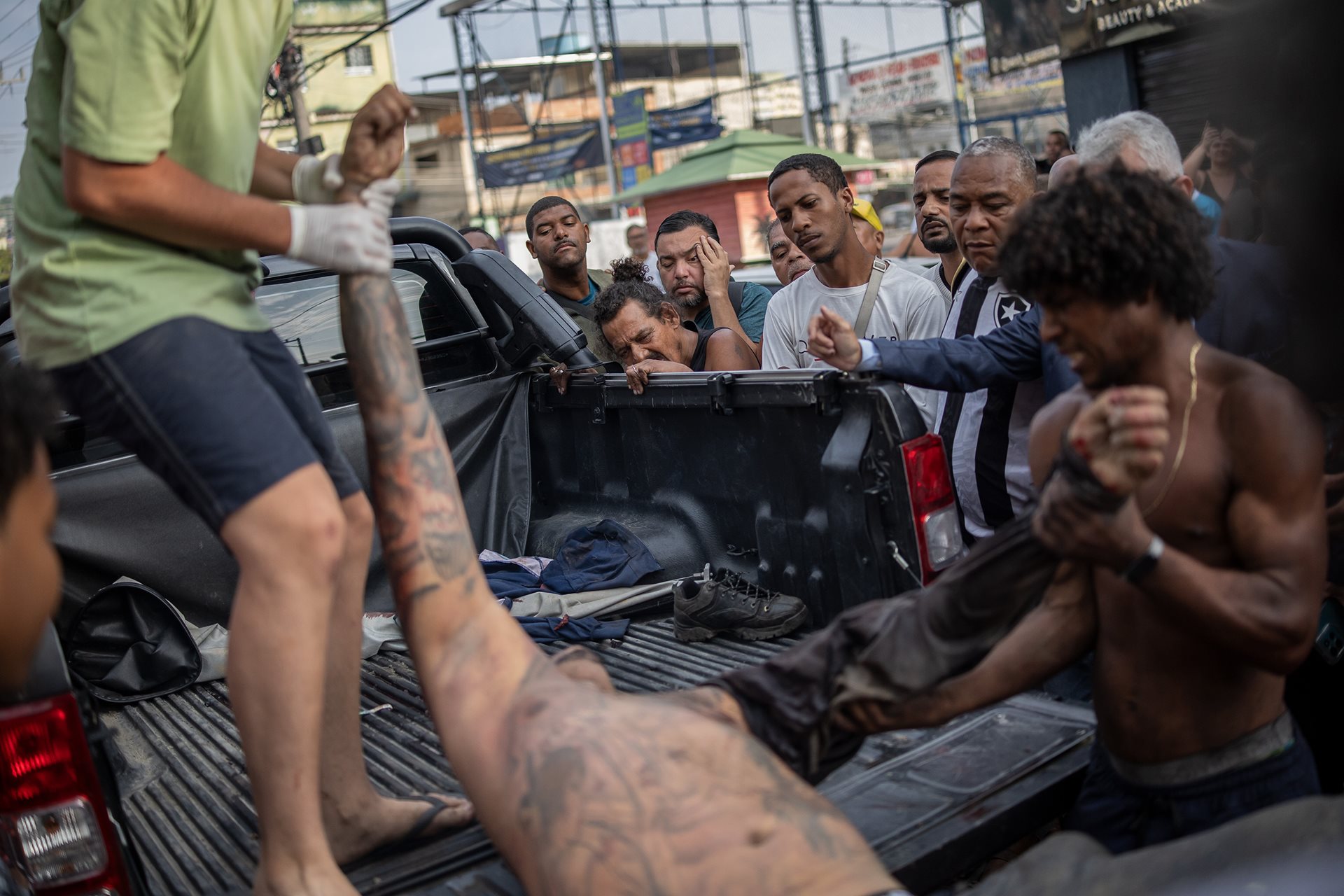 Community members help remove a body from a pickup truck in São Lucas Square, Rio de Janeiro, Brazil. Residents spent hours transporting the deceased to this central collection point because civil police chiefs did not deploy crime scene analysts or medical personnel to the area.&nbsp;