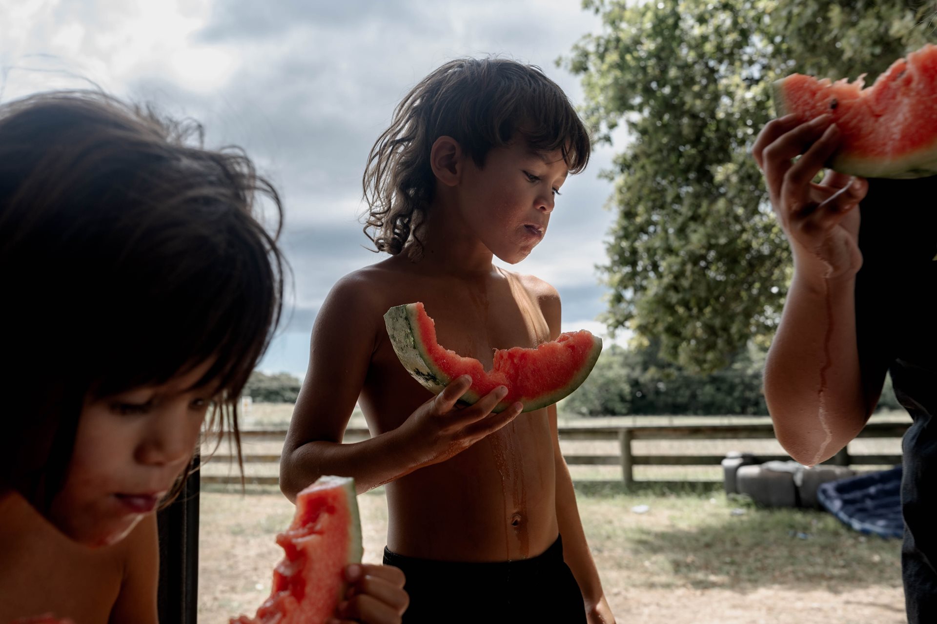 Teepa children share a watermelon on the family farm in Ruatoki, New Zealand. John Rangikapua Teepa and his wife Carol have raised more than 20 children adopted according to the Māori whāngai custom, to strengthen traditions and family ties. Whāngai children often maintain relationships with both birth and adoptive families. This open arrangement helps preserve cultural heritage and strengthens family ties.