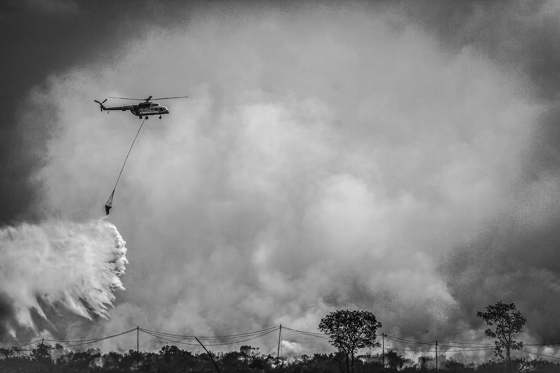 A helicopter releases water to extinguish a fire in a peatland forest in the Ogan Ilir district of South Sumatra, Indonesia.