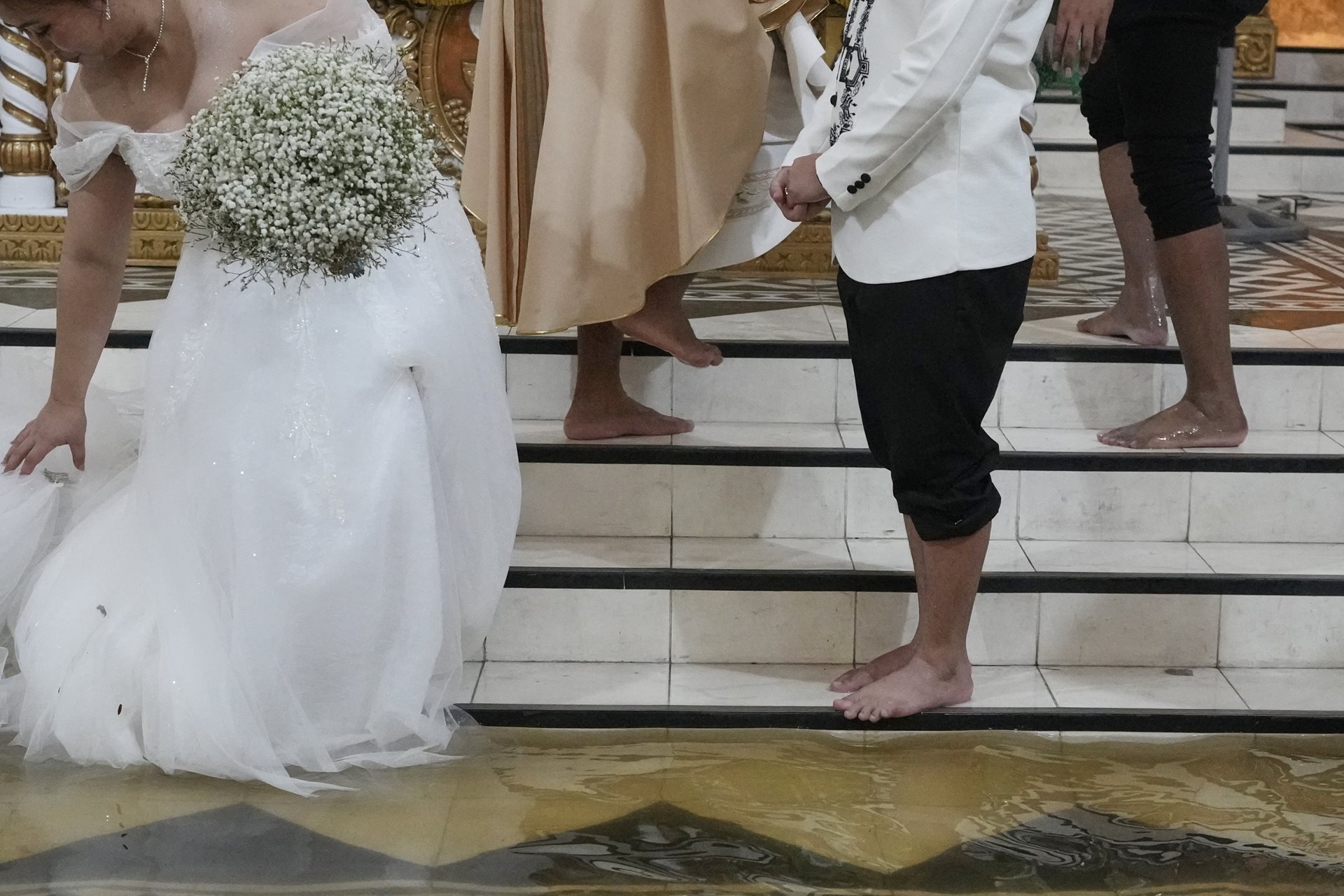 Jamaica Aguilar, left, arranges her gown beside her barefoot groom, Jade Rick Verdillo. To prevent flood-borne diseases such as leptospirosis, the couple took antibiotic doxycycline pills from their local health center before the wedding. Malolos, Bulacan province, Philippines.