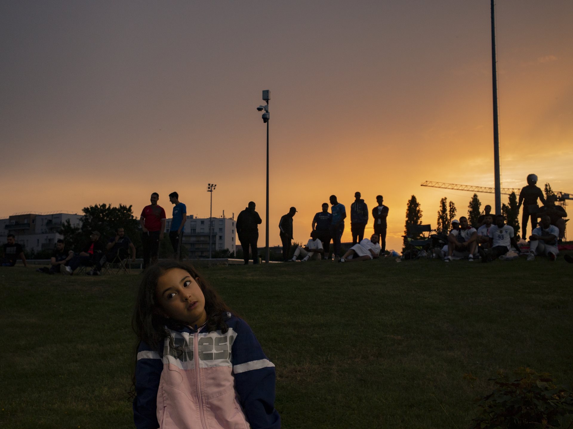 Spectators watch from a hill during the African Cup of Nations of Aulnay, a local amateur soccer tournament bringing together French citizens of African origin, part of a growing movement of community competitions across the banlieues. Aulnay-sous-Bois, France.