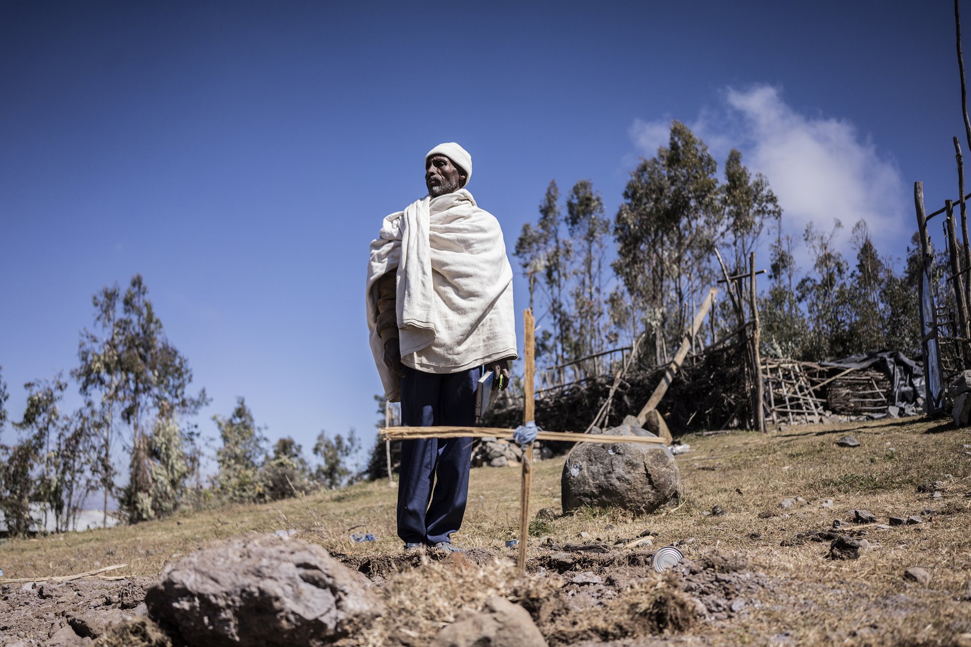 Wubeshet Debbie stands in front of a grave in Mesobit, Amhara, Ethiopia.