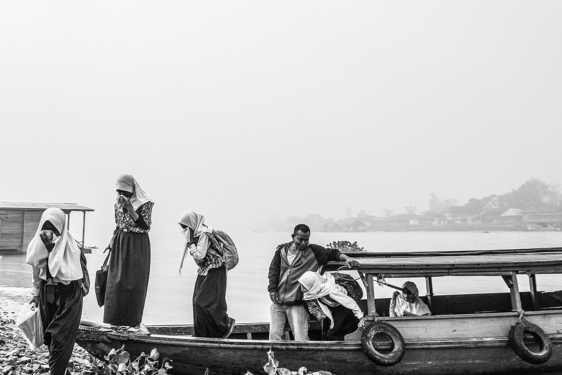 Women cover their faces against smoke haze from forest fires, as they disembark from a boat in Palembang, South Sumatra, Indonesia.