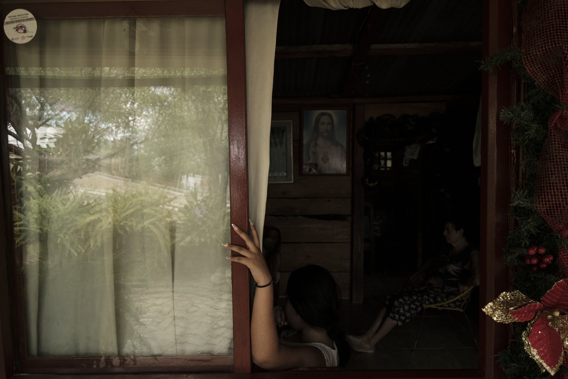 María (20), the photographer&rsquo;s cousin, watches television with her grandmother, Orfelina, in Los Patios, Norte de Santander, Colombia. In Ospina&rsquo;s family, there are 12 women, including mothers, sisters, and daughters, but only three adult men.