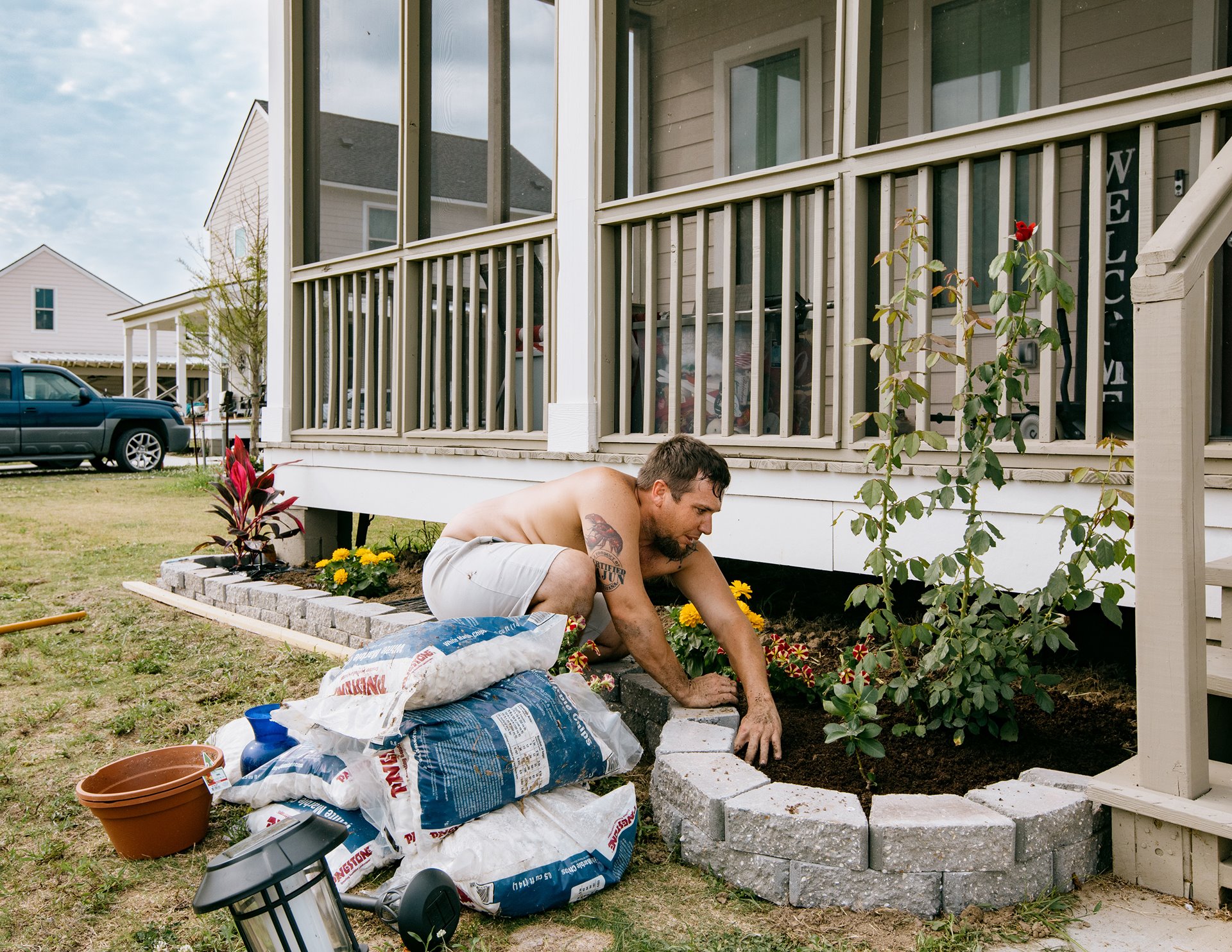 Jay plants flowers in the beds around his home in Gray, six months after moving in from Isle de Jean-Charles. Gray, Louisiana, United States.