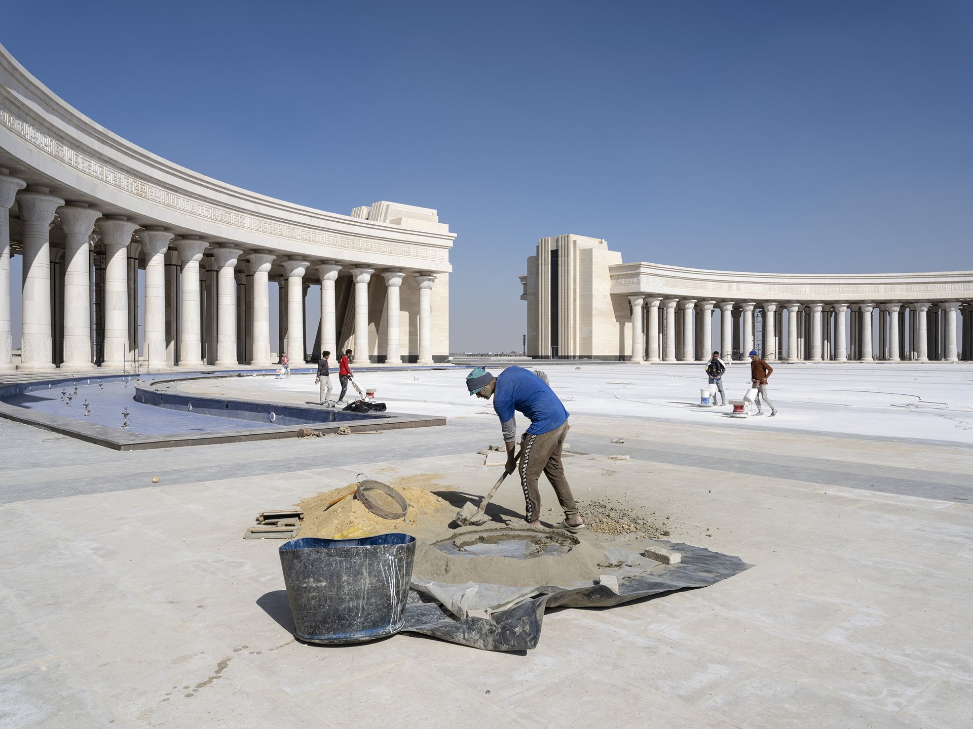 <p>Workers fill joints between paving stones at the Arc de Triomphe, situated between the Presidential Palace and the House of Representatives in Egypt&#39;s New Administrative Capital, under construction near Cairo.</p>
